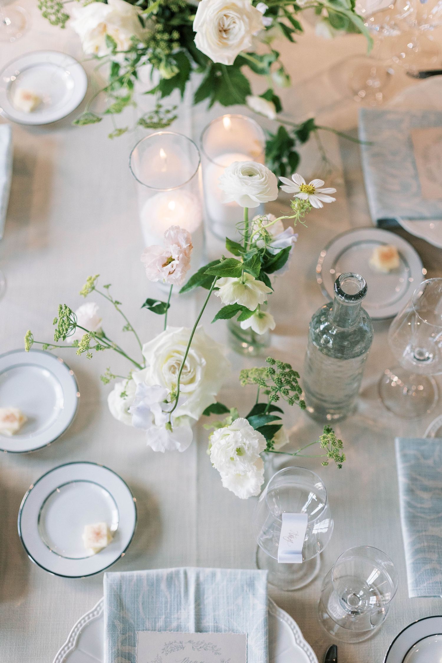 Overhead view of wedding table setting with white roses, candles and crystal glassware.
