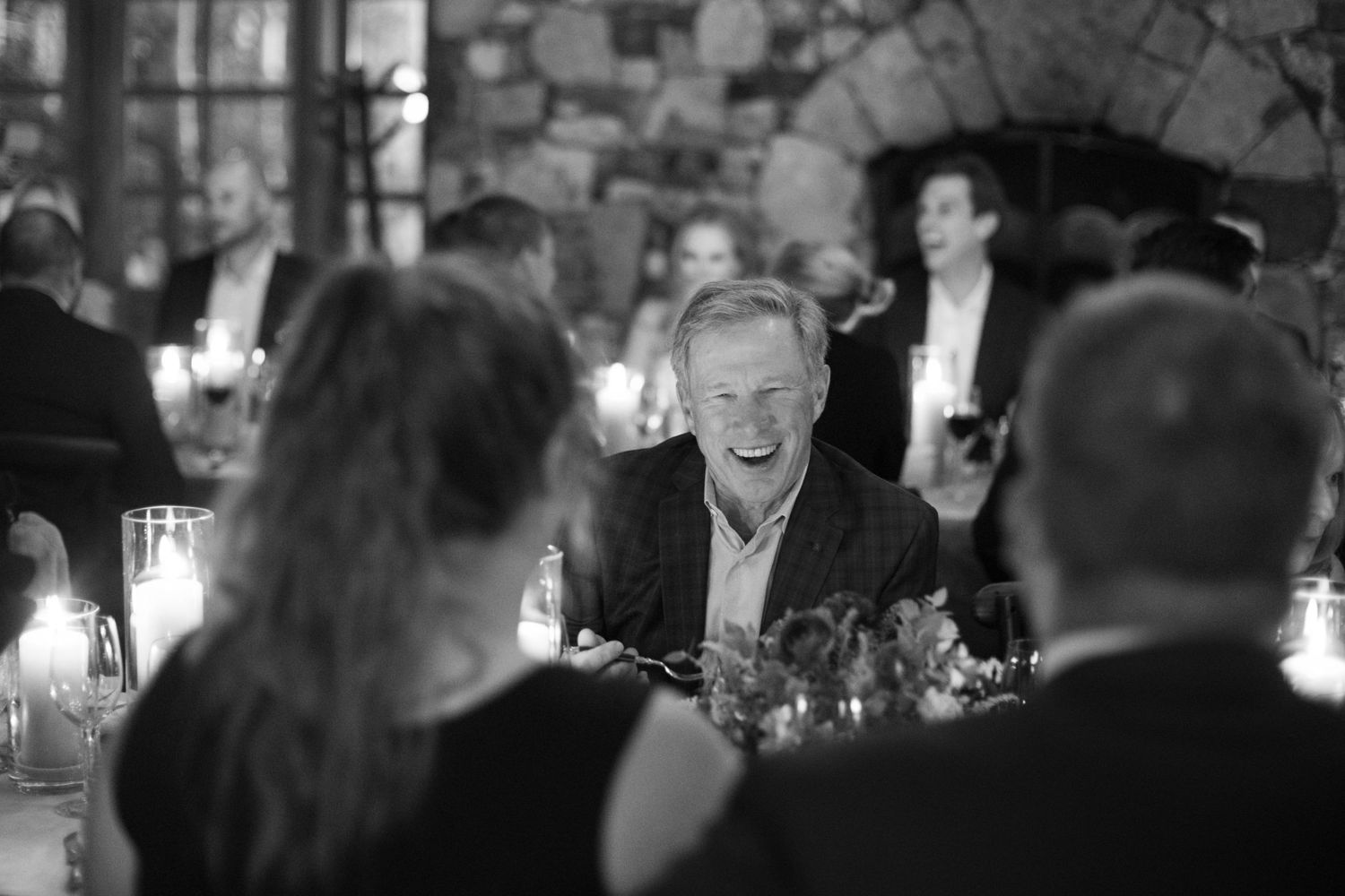 Black and white photo of guests enjoying a lively moment during an indoor reception dinner.
