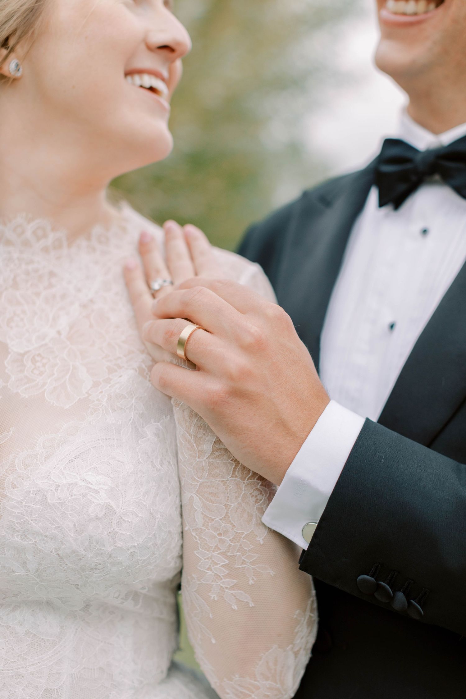 Close up of couple's hands showing wedding ring and lace dress details.