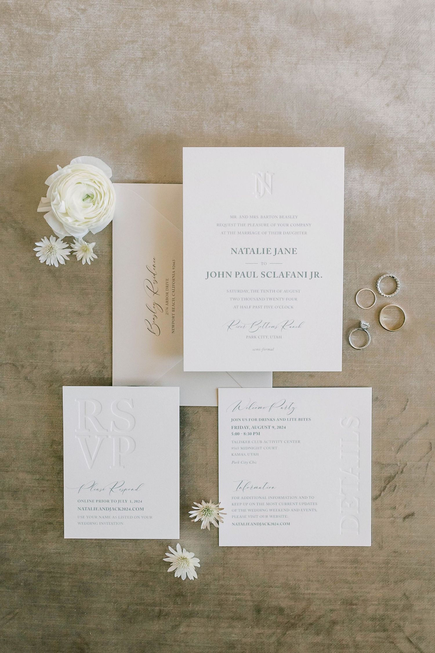 Minimalist white wedding invitation suite with floral accents and wedding rings.