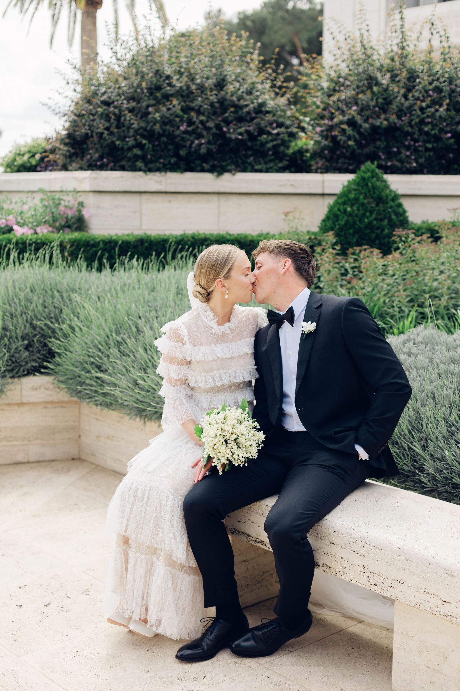 wedding couple sharing romantic moment on garden bench surrounded by greenery at rome lds temple.