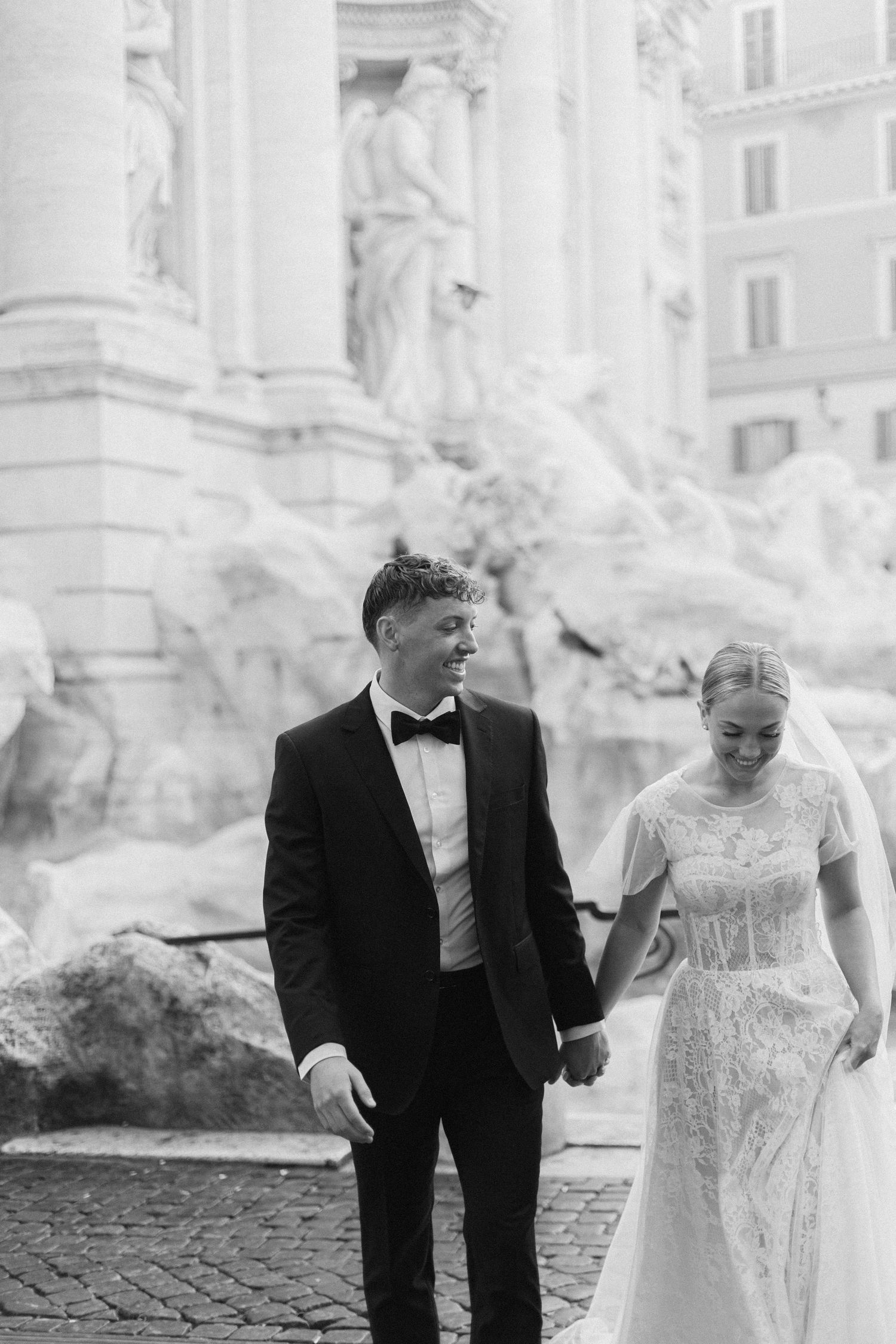 Black and white wedding portrait by the Trevi Fountain capturing a candid moment.