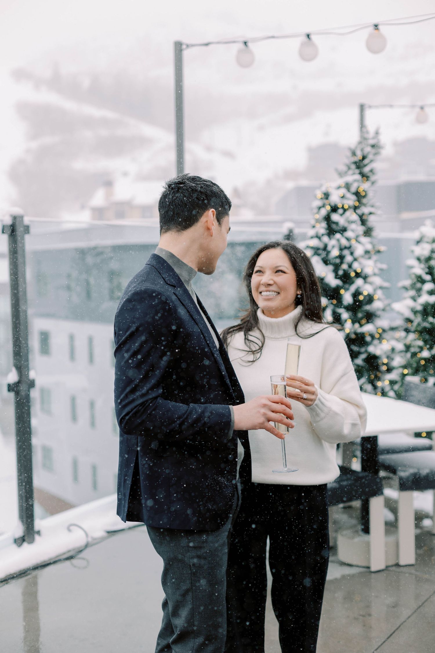Couple sharing drinks on snowy rooftop with Christmas decorations at pendry park city.
