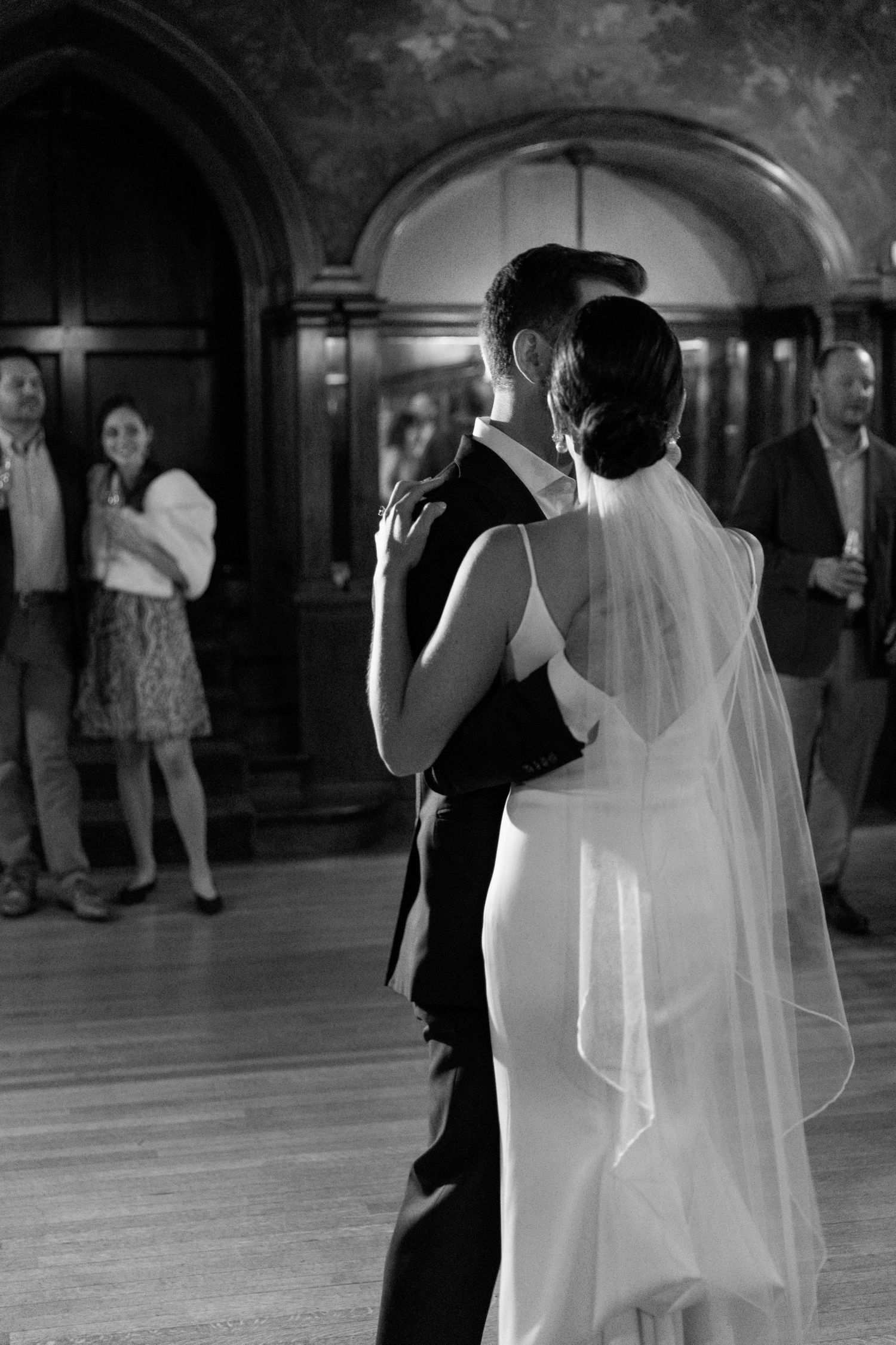 A romantic dance moment captured in black and white under arched architectural details.