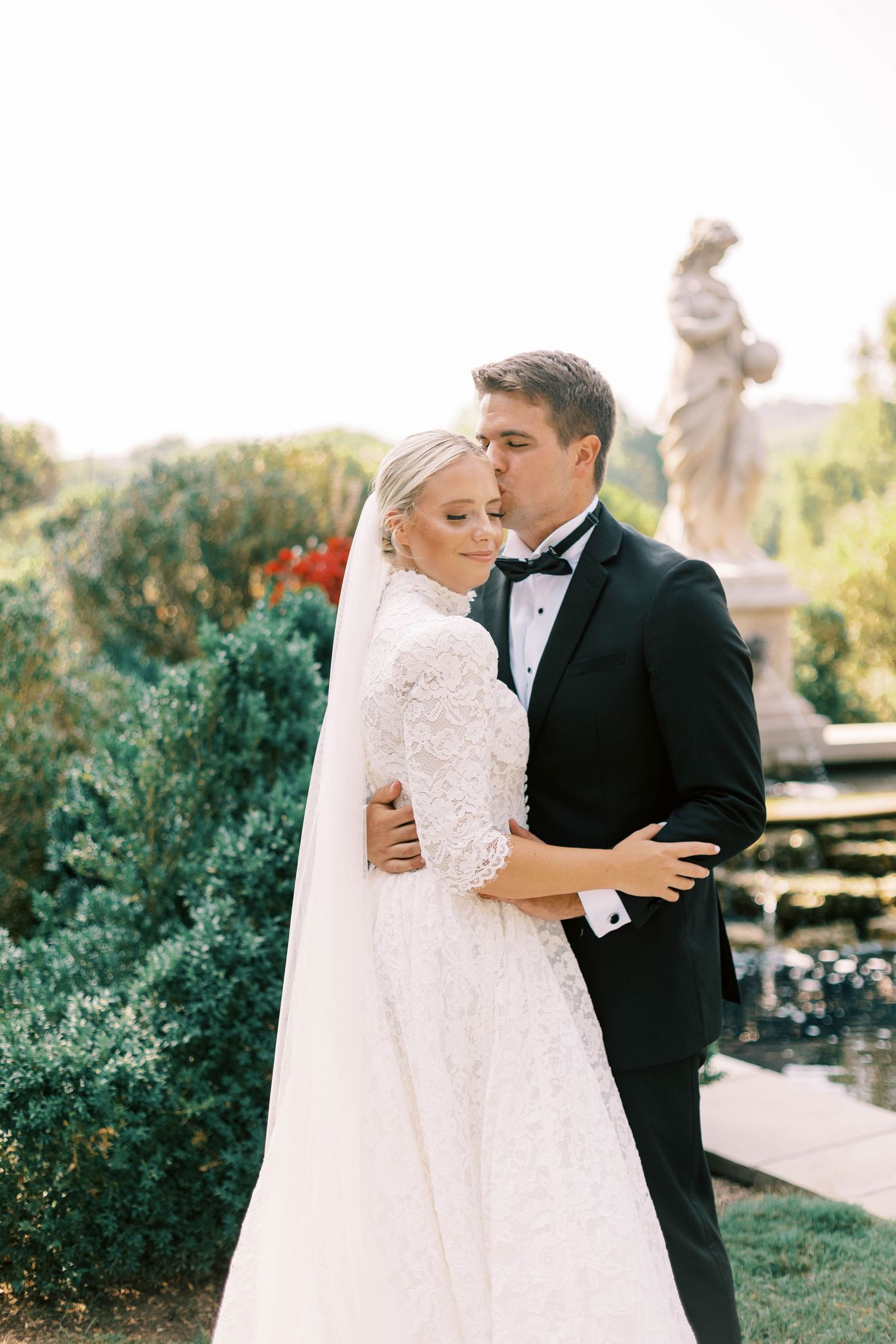 Romantic wedding portrait in a garden setting with classical statue and manicured hedges of Cheekwood Estate.