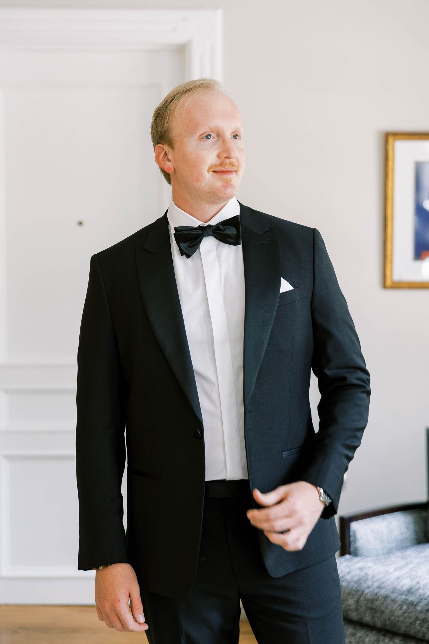 Classic black tuxedo with bow tie and crisp white shirt in an elegant interior setting.