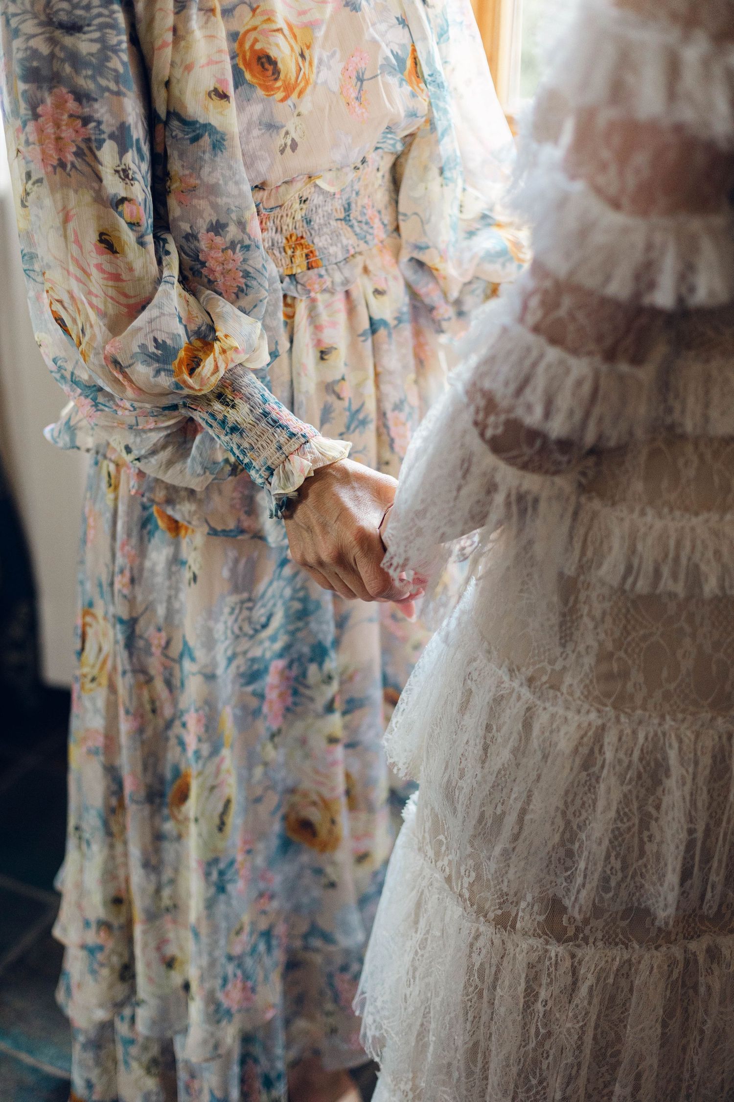 Detail shot of floral print dress and white tiered lace gown.
