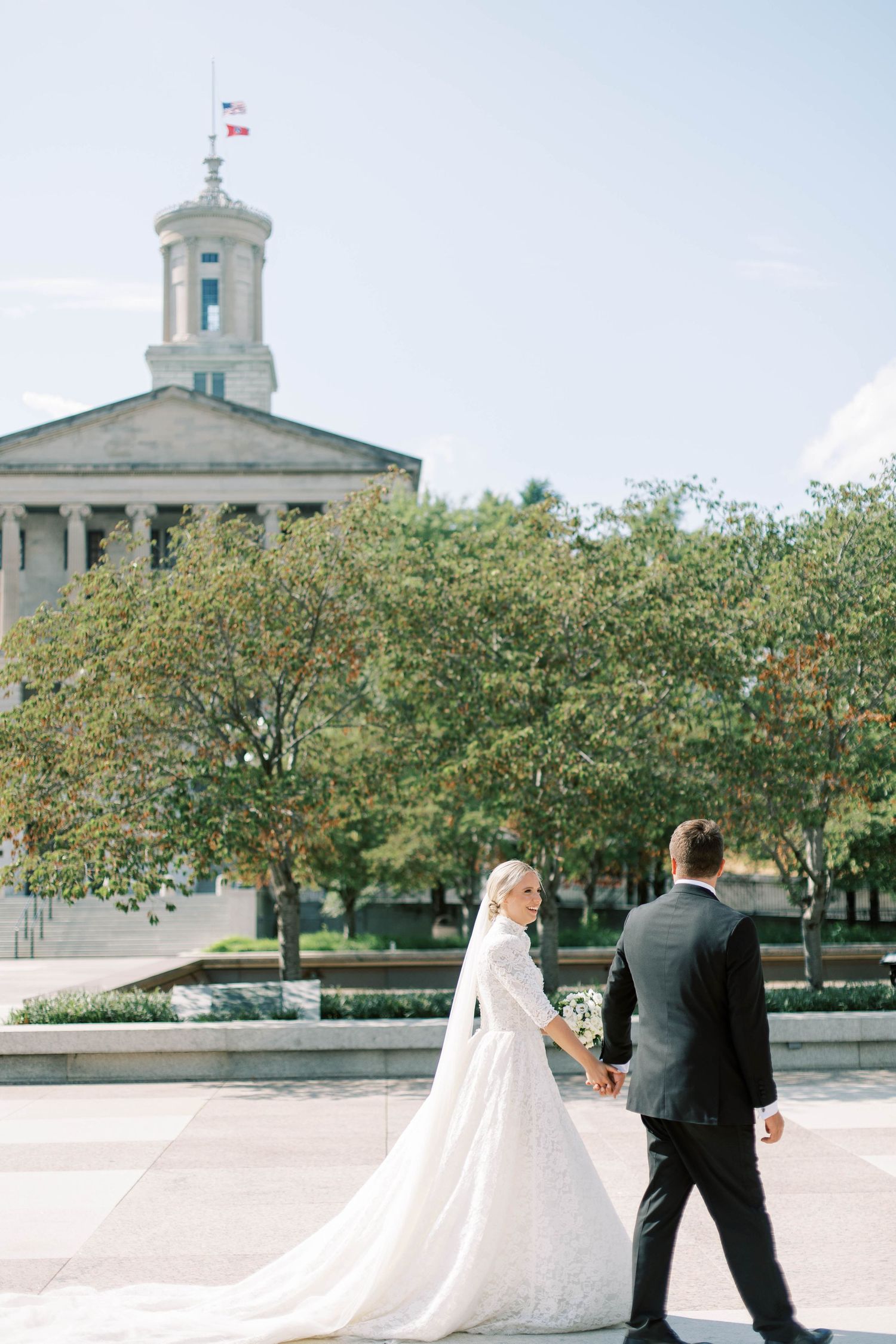 Wedding couple photographed in front of Tennessee State Capitol with its iconic dome and autumn trees.