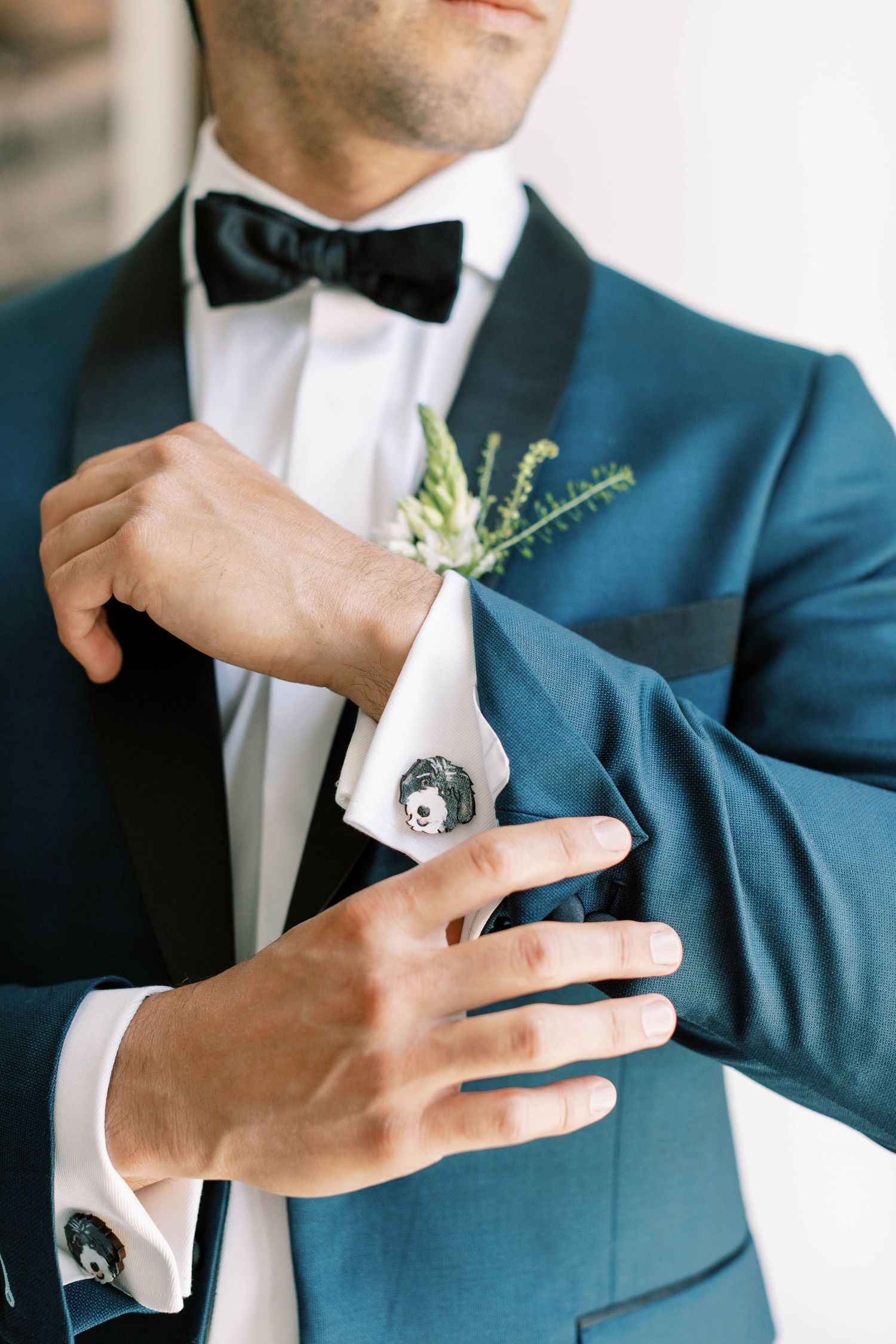 Detailed shot of blue tuxedo with boutonniere and bow tie.