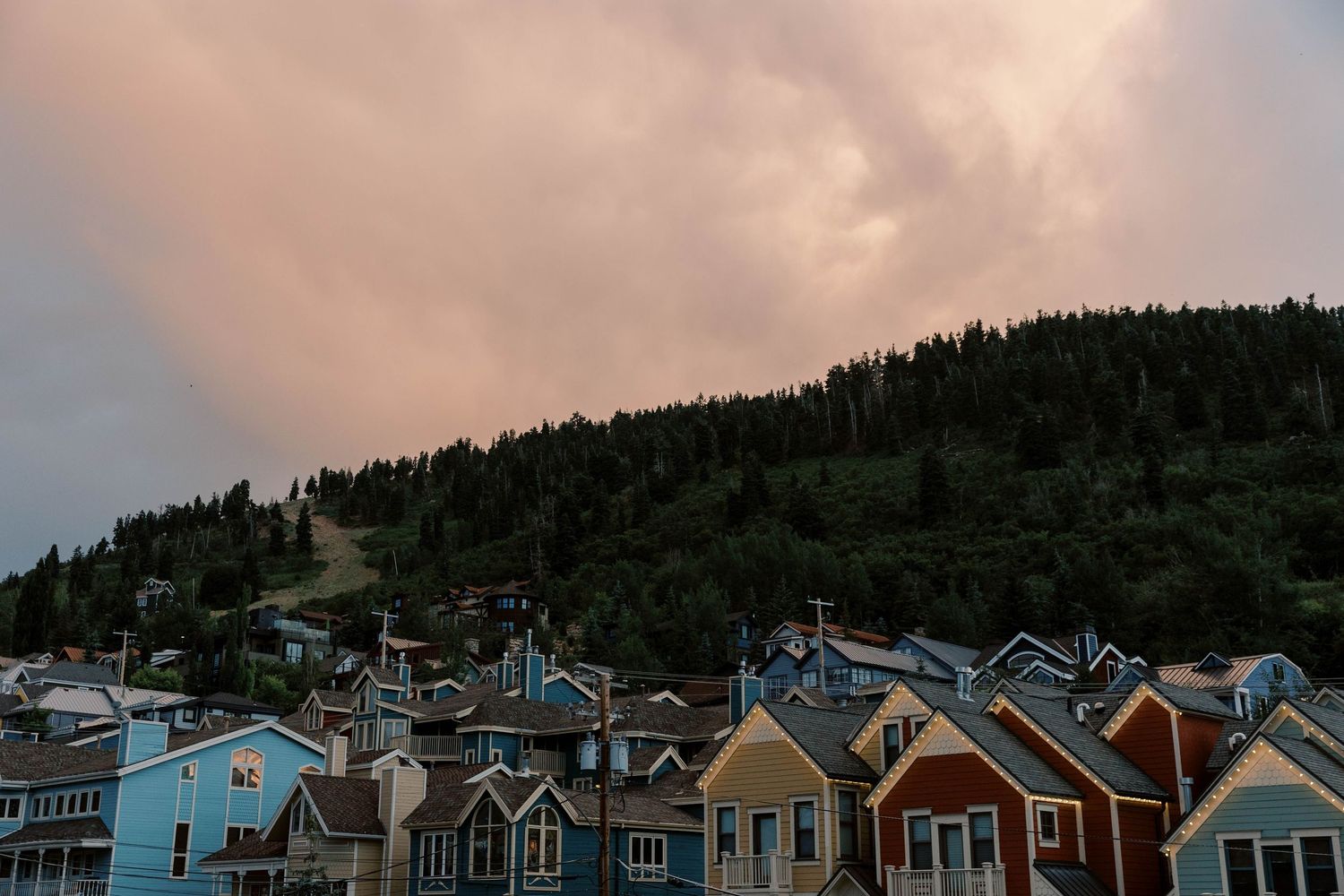 Colorful row of park city houses line hillside beneath dramatic pink sunset sky.