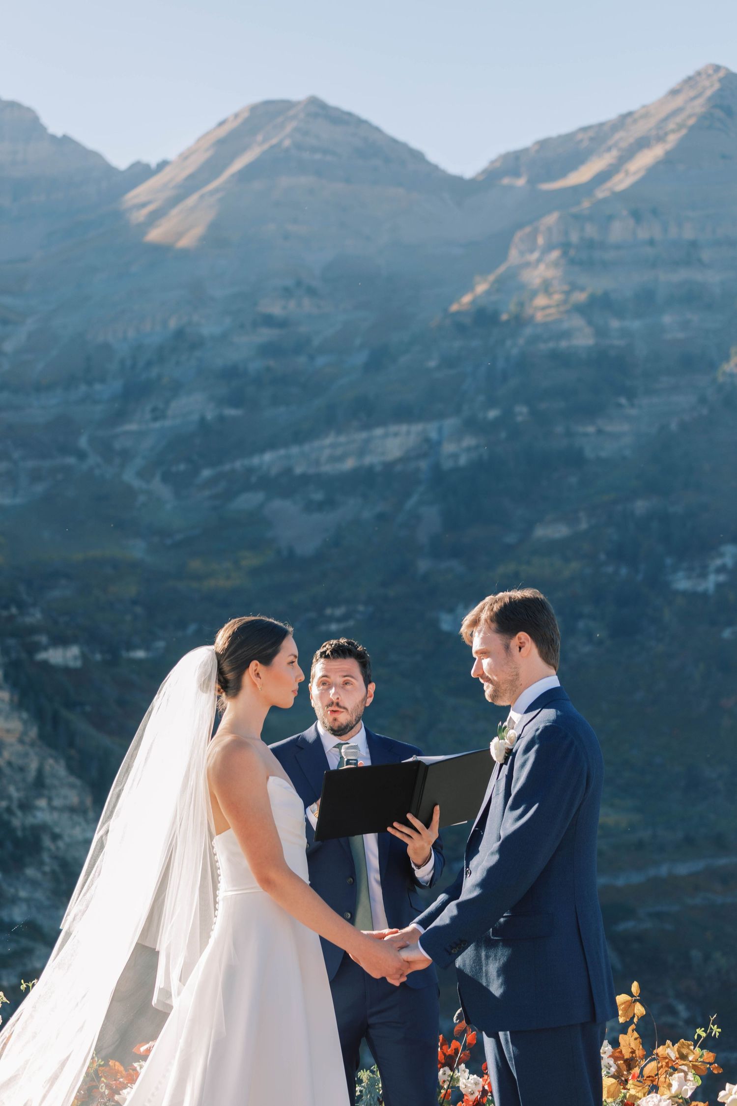 Mountain wedding ceremony with dramatic peaks and cliffs in background.
