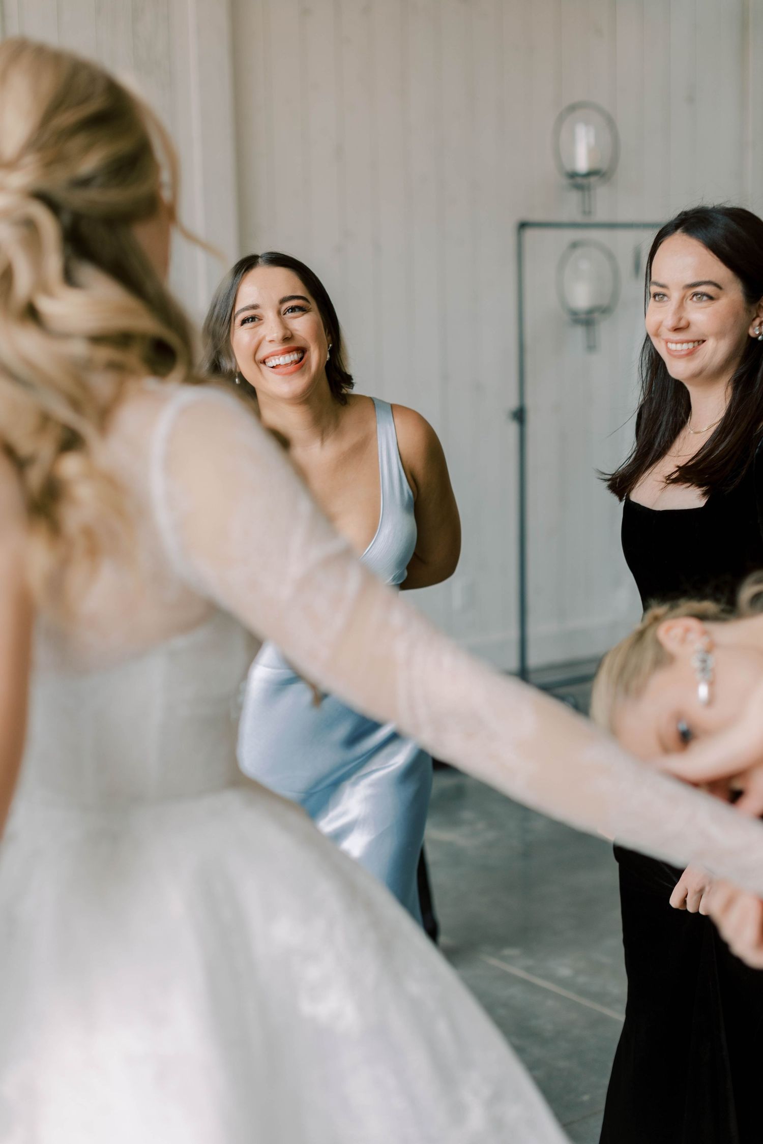 Joyful moment between bride in white gown and bridesmaids getting ready for wedding.