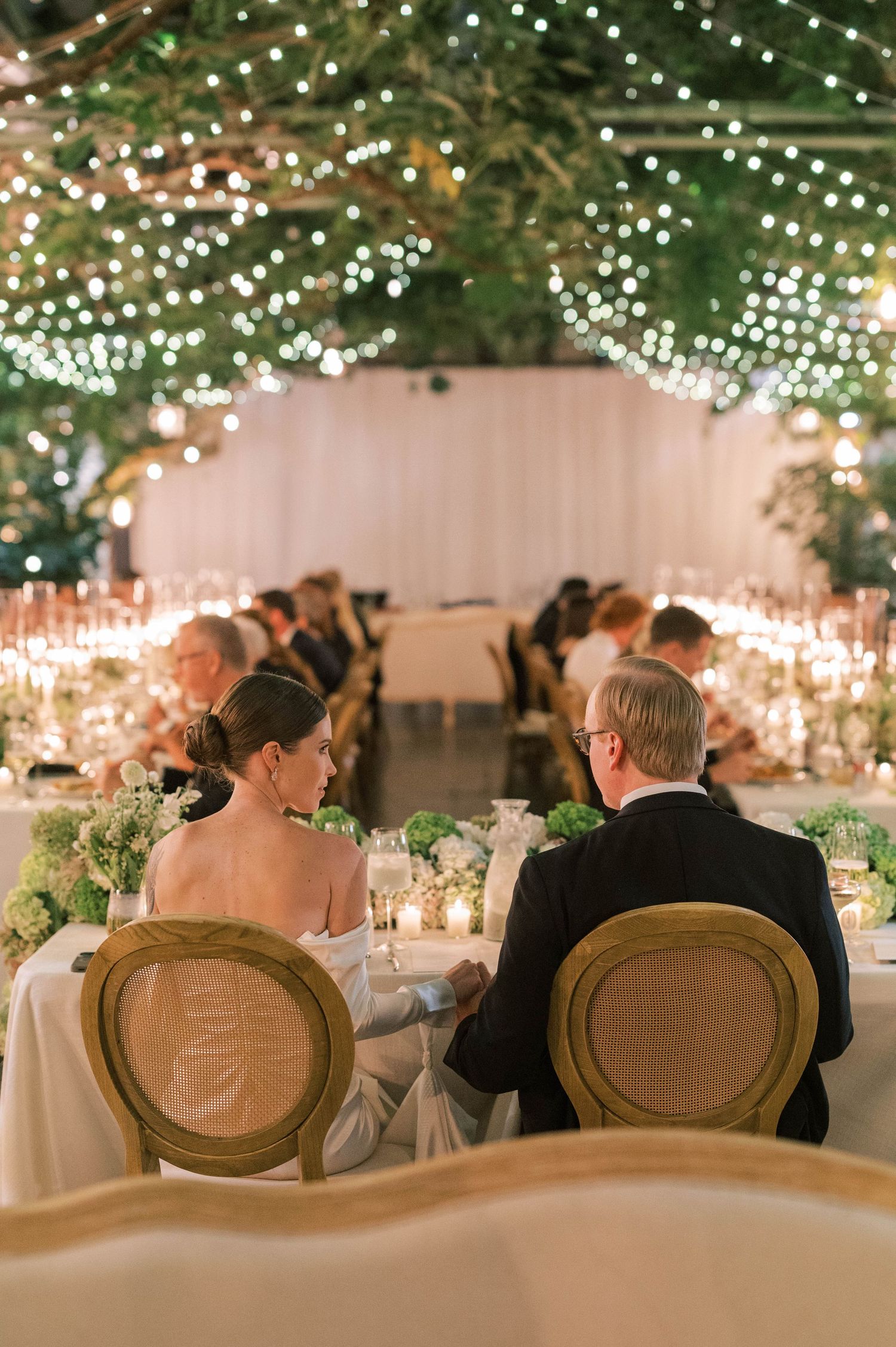 Wedding reception venue decorated with twinkling fairy lights and greenery creating a magical atmosphere.