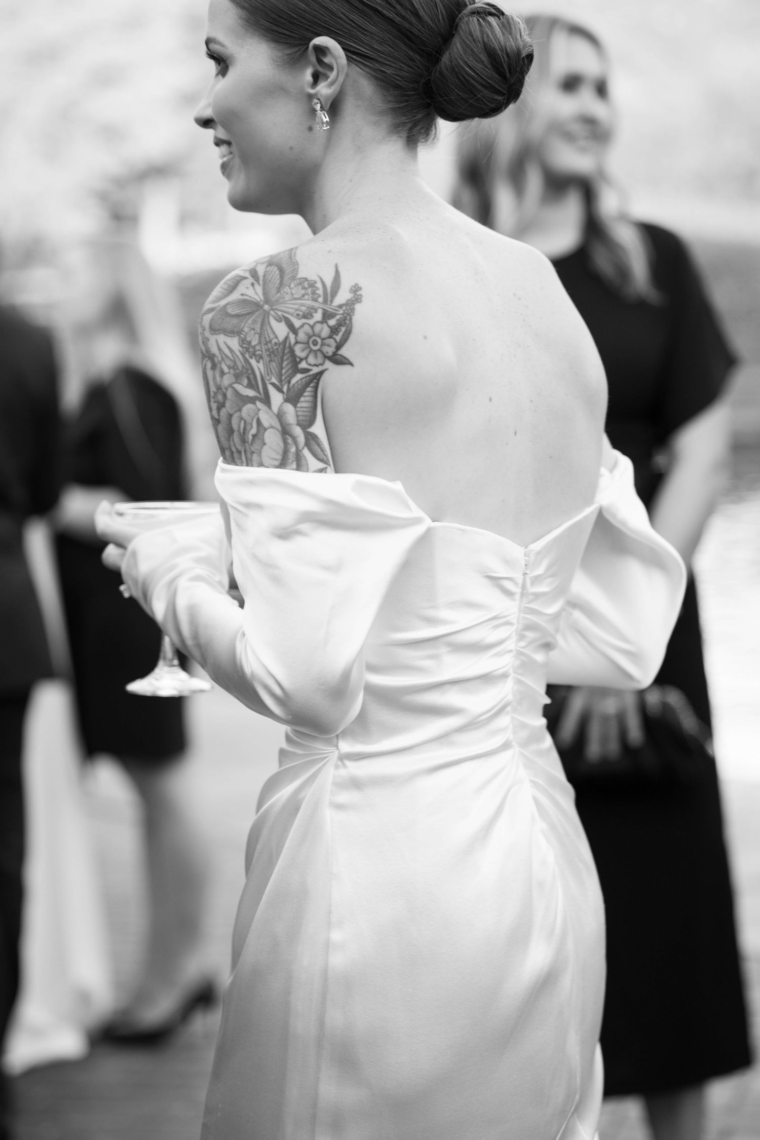 A wedding dress reveals an elegant floral back tattoo in black and white.