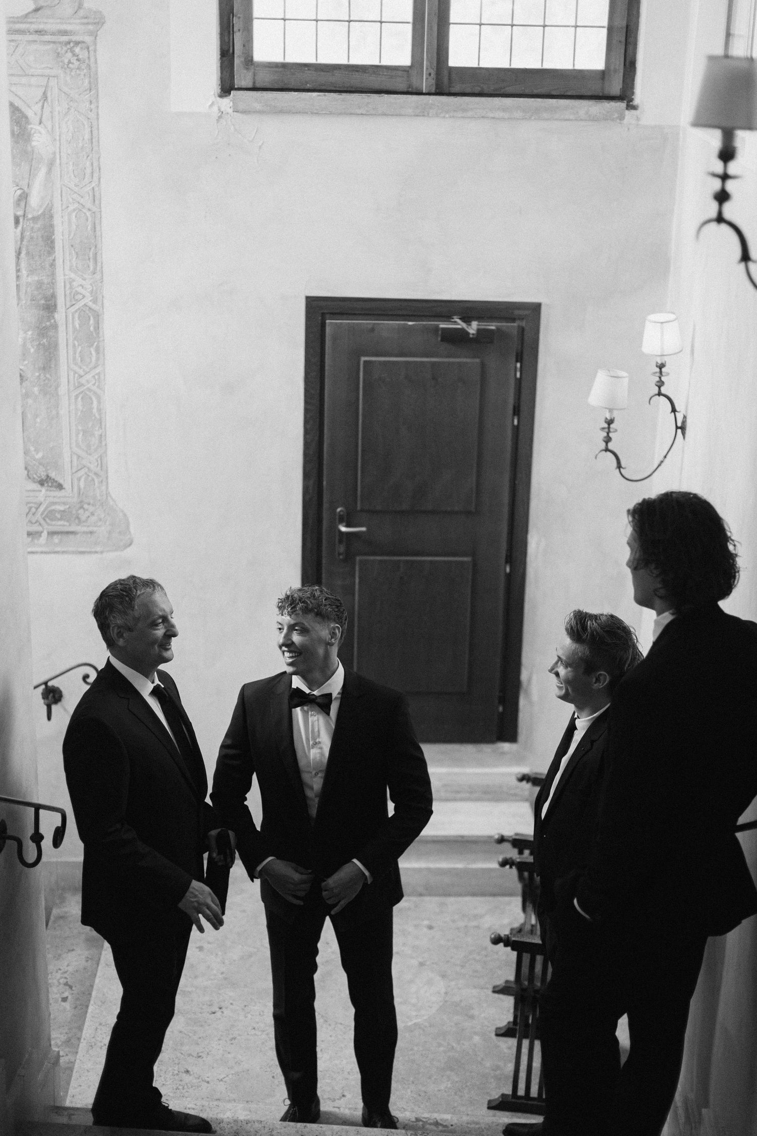 Black and white photograph of formal gathering in historic interior space.