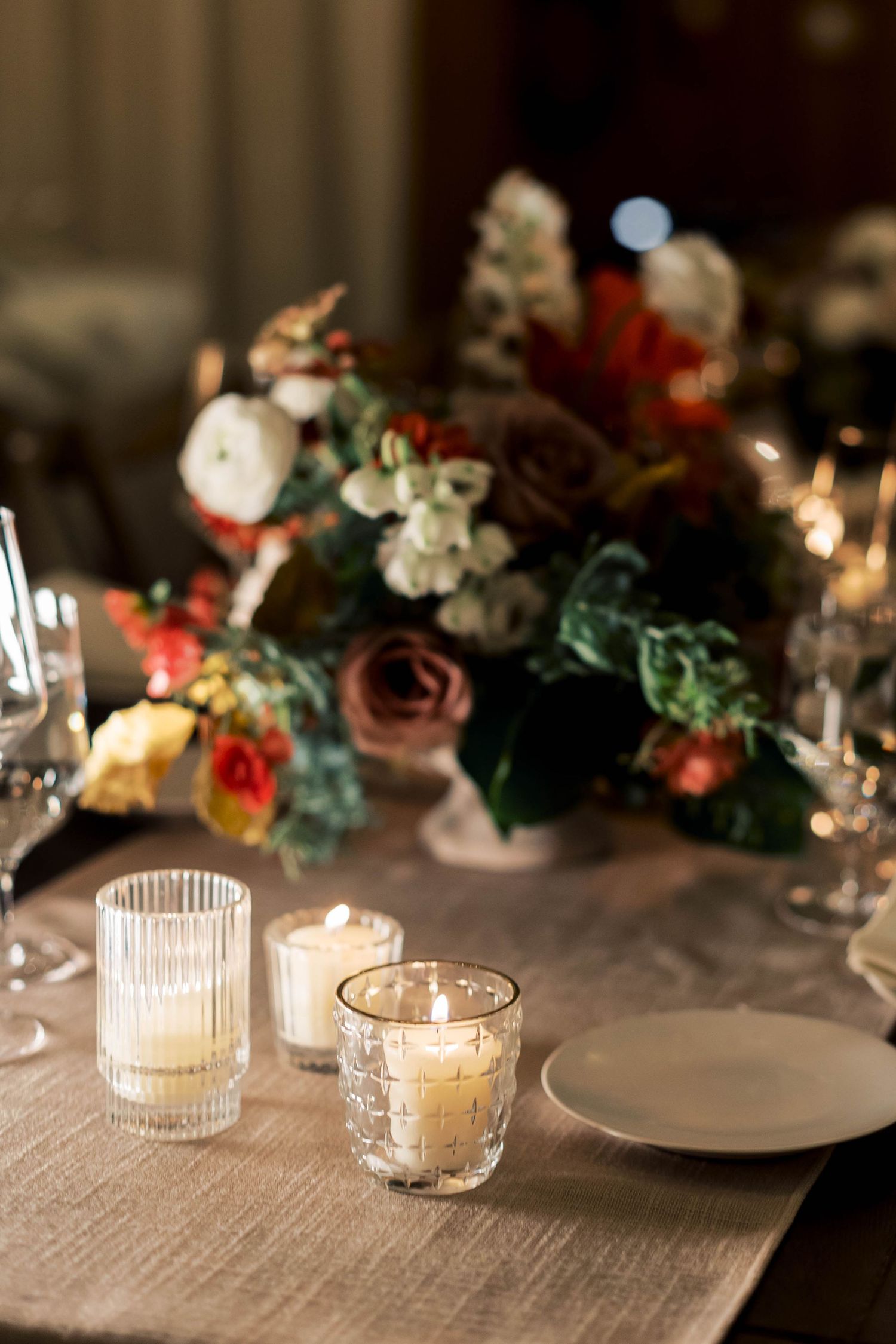 Elegant table setting with floral centerpiece, candles, and wine glasses in warm evening light.