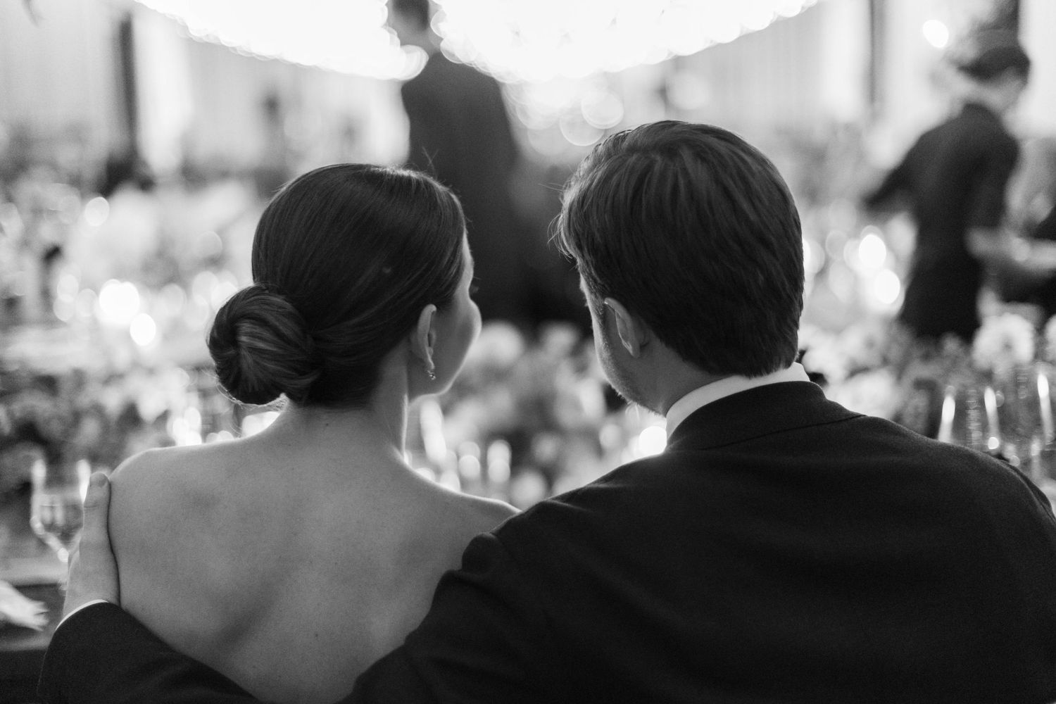 Black and white photo of a couple sitting together at an elegant wedding reception.