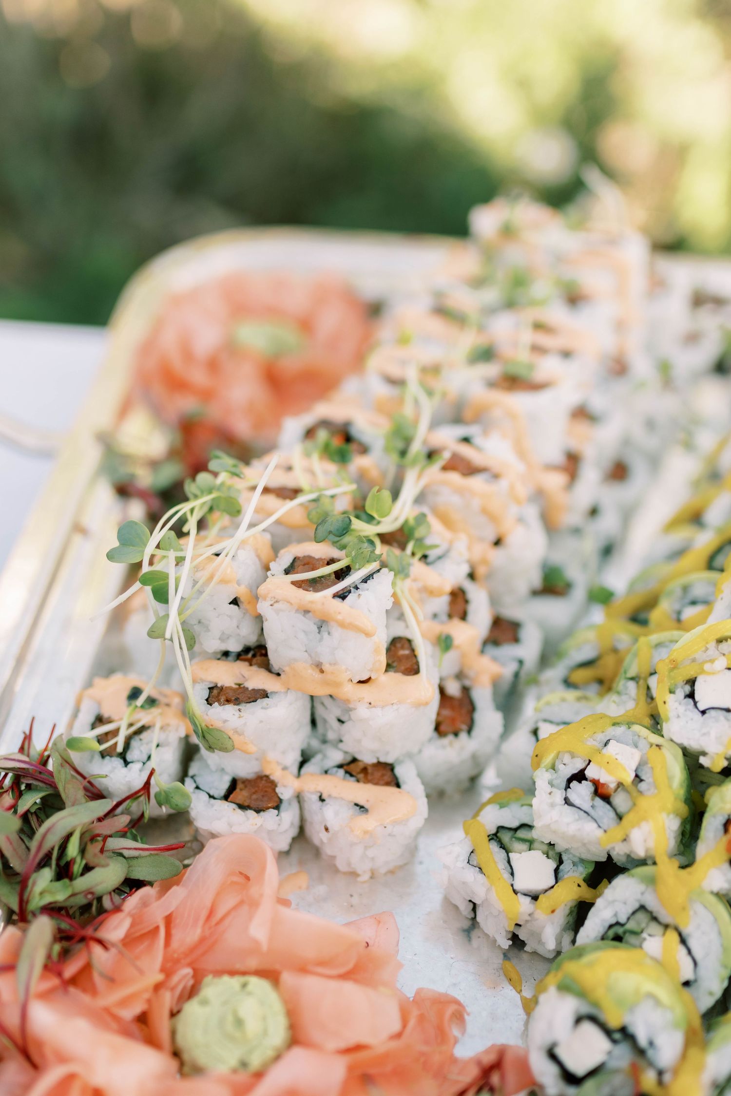 Beautifully plated assortment of colorful sushi rolls garnished with microgreens.