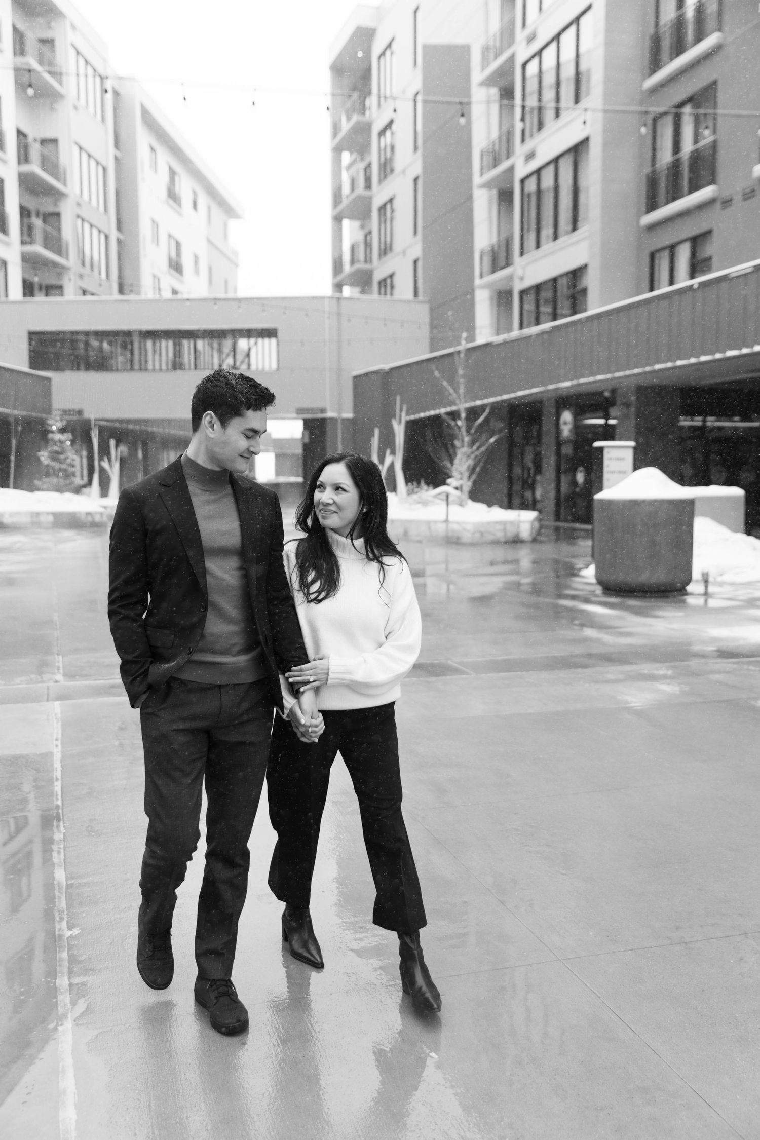 Couple walking together on wet sidewalk in winter attire at the pendry park city.