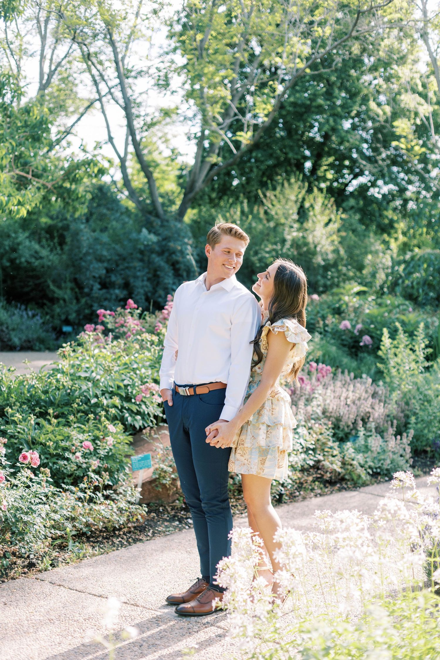 A sunny garden scene with blooming flowers as couple shares a tender moment.