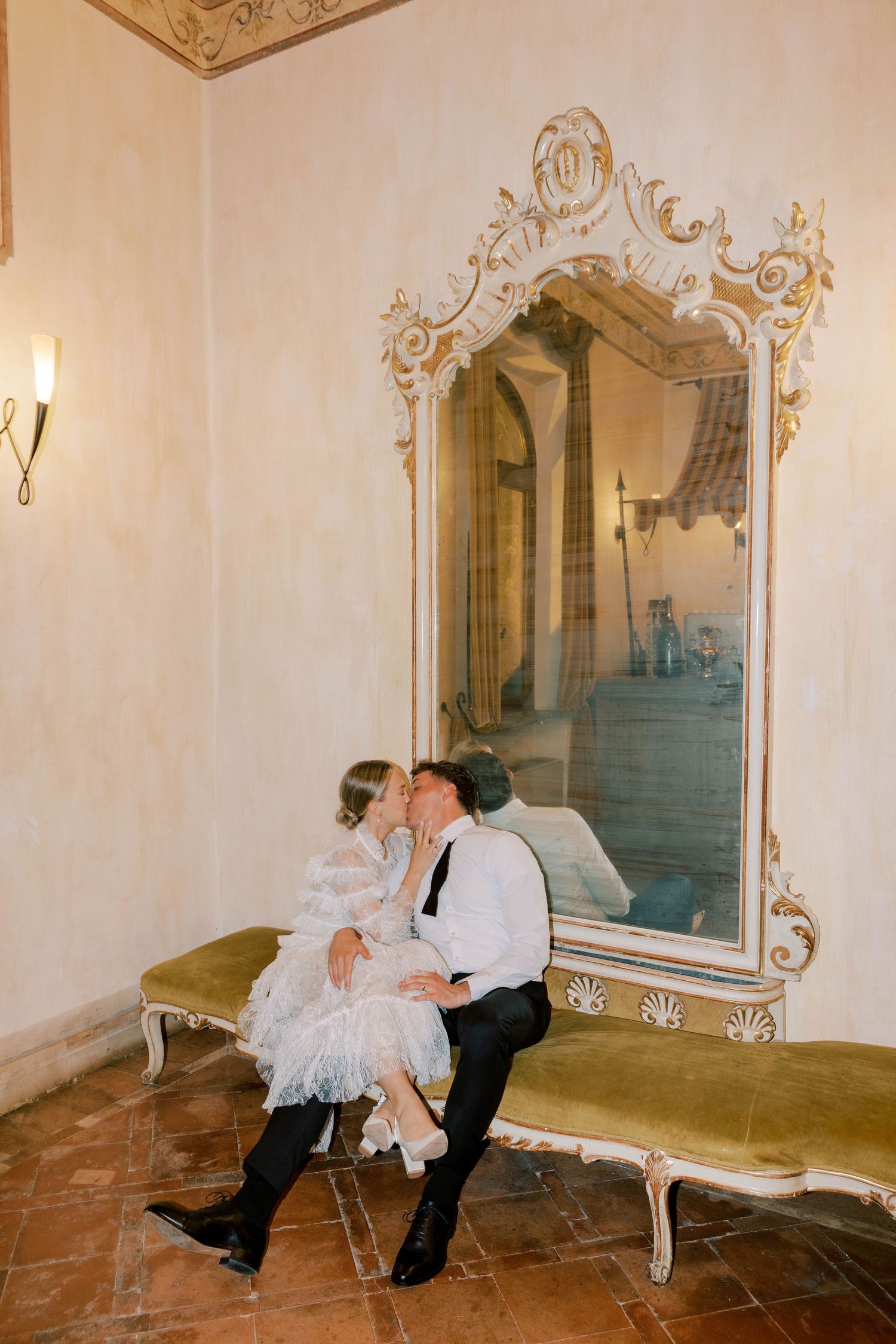 Romantic moment captured in an elegant room with ornate gold mirror at castello della castellucia.