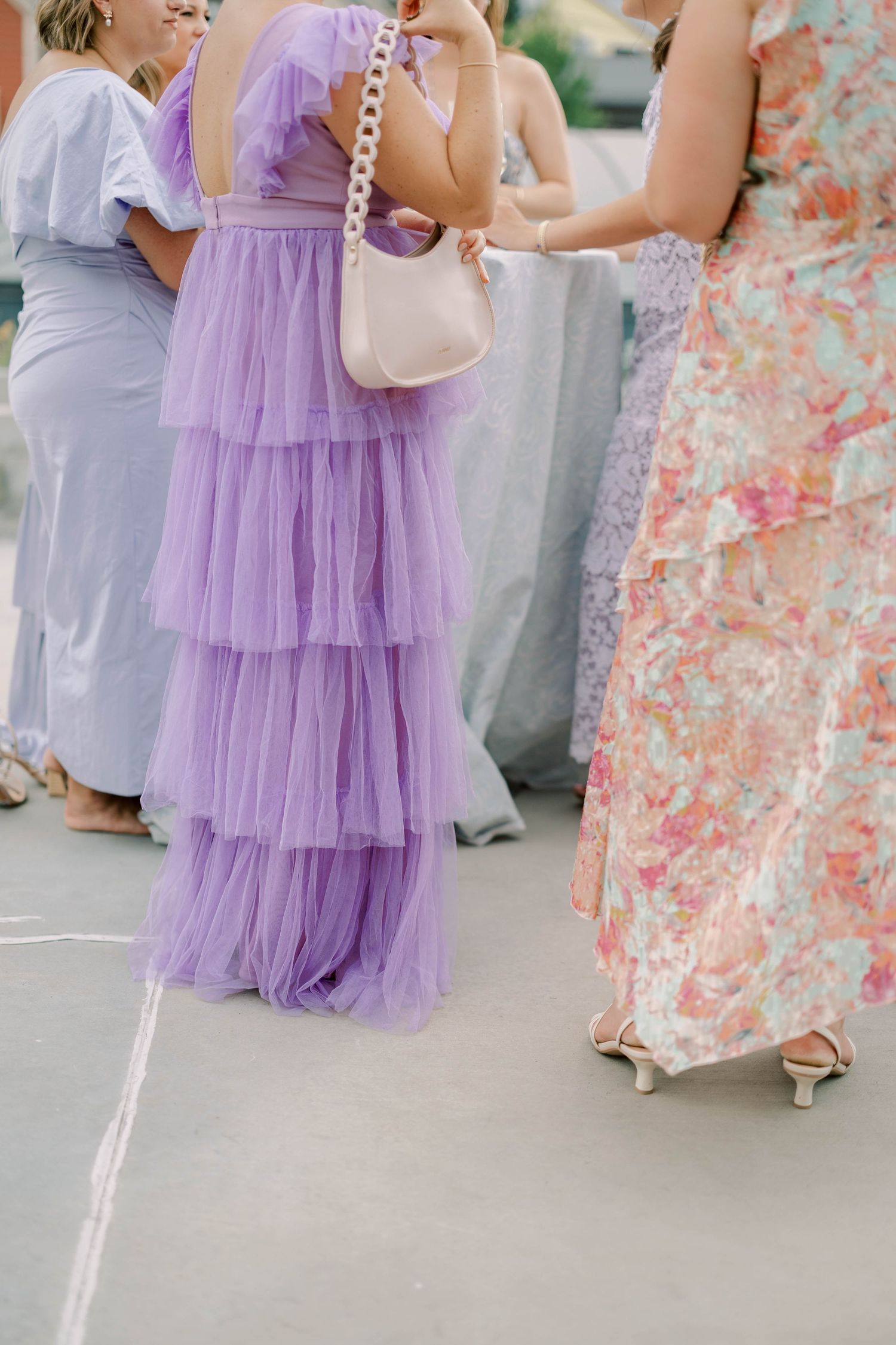Wedding guests in pastel dresses with tiered tulle skirts at outdoor reception.
