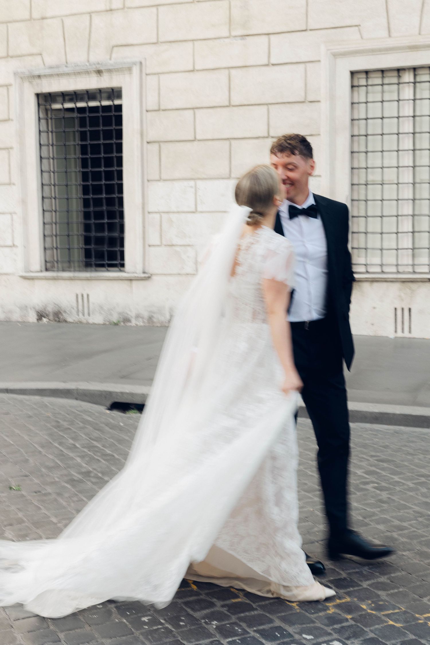 Newlyweds share a candid moment on cobblestone streets of rome Italy.