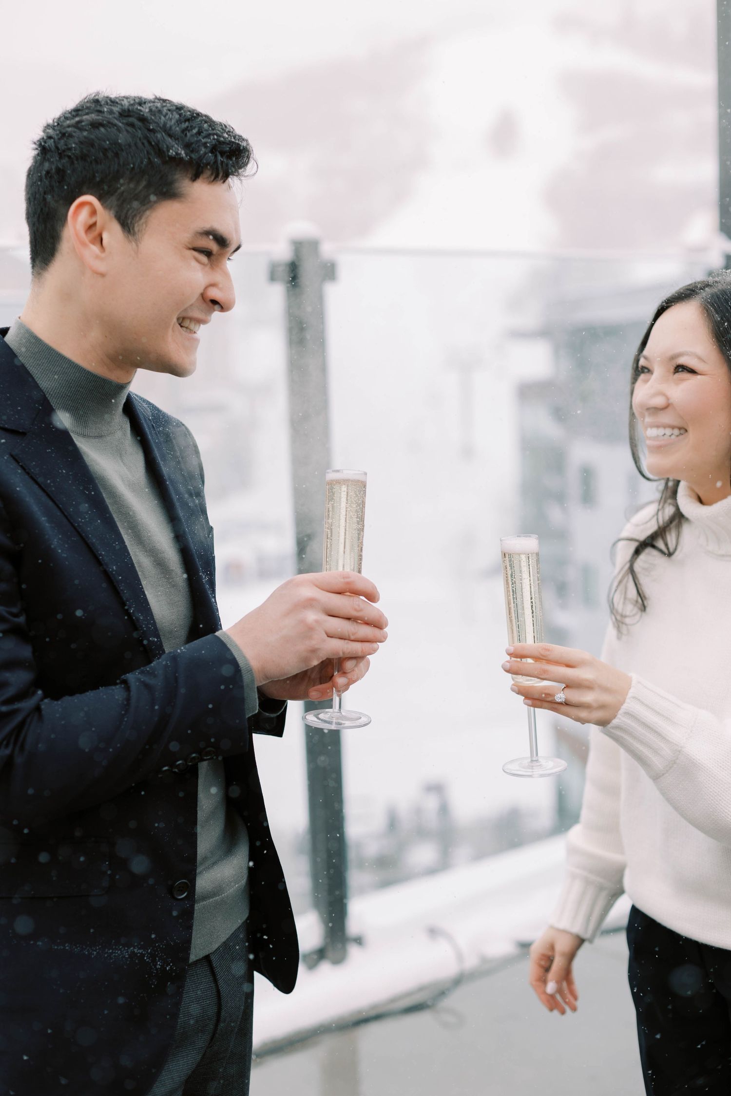 A joyful celebration moment shared over champagne on a snow-covered terrace.