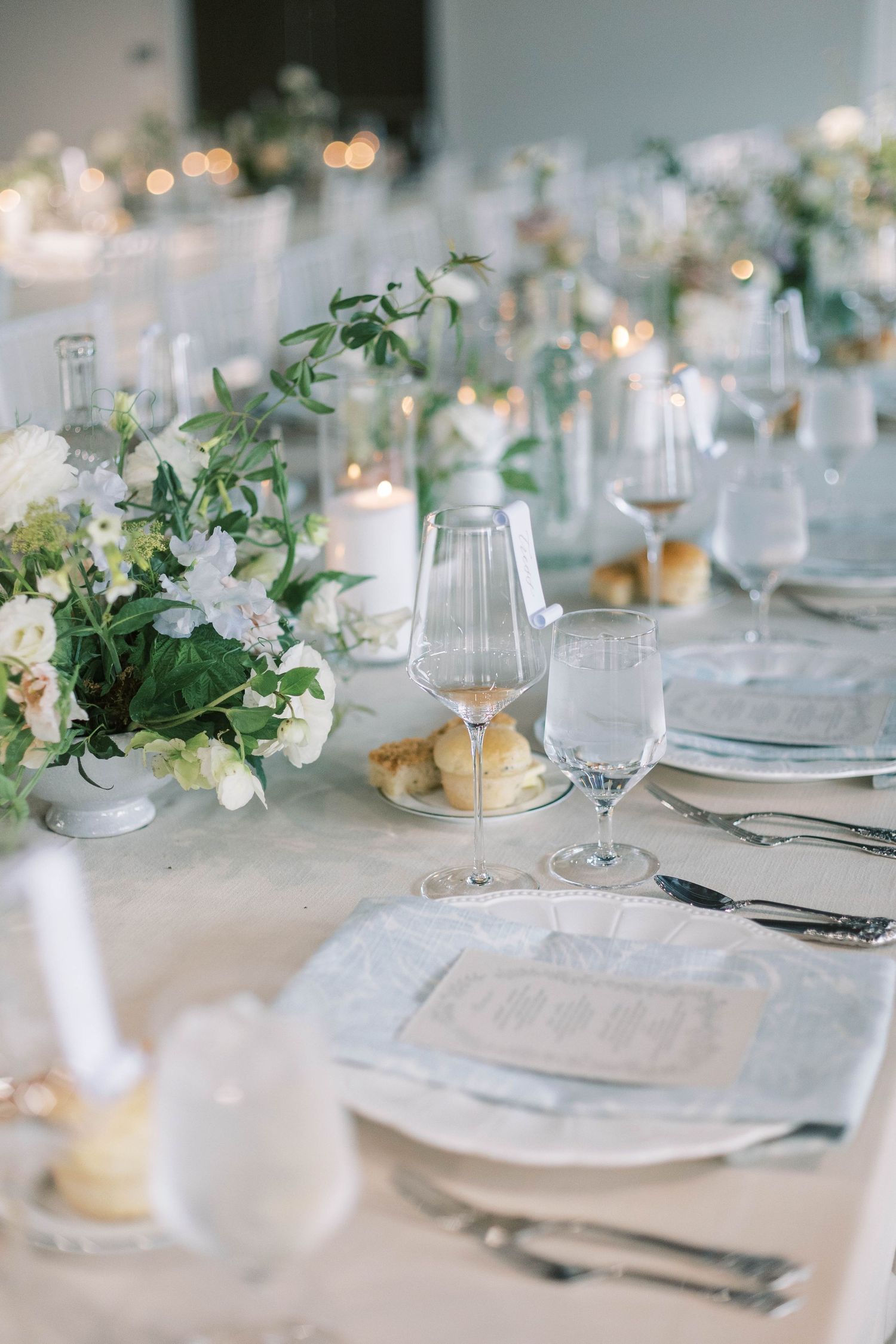 Elegant table setting with white floral centerpieces, candles, and crystal glassware.