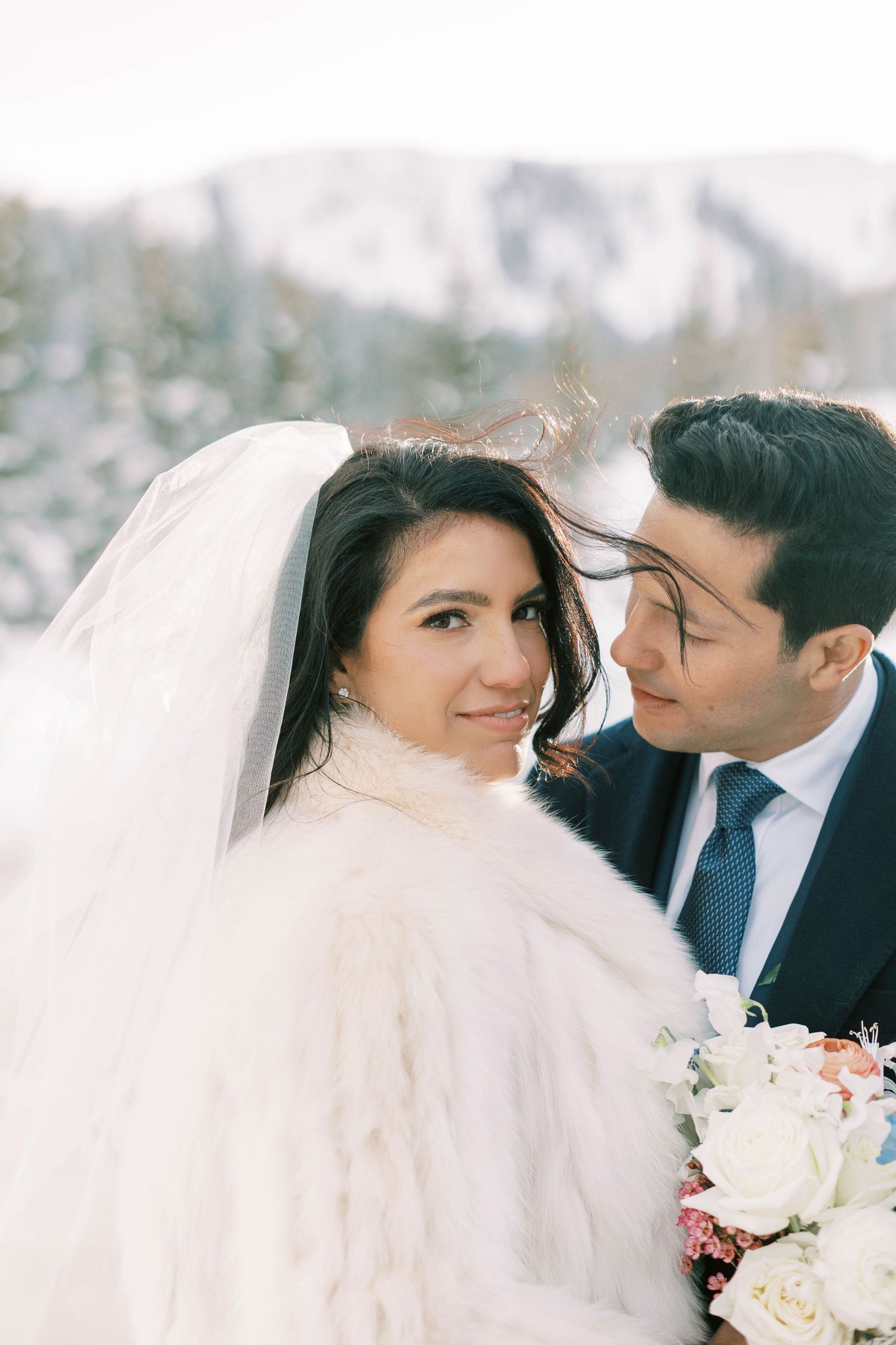 Intimate winter wedding portrait against snowy mountain backdrop.