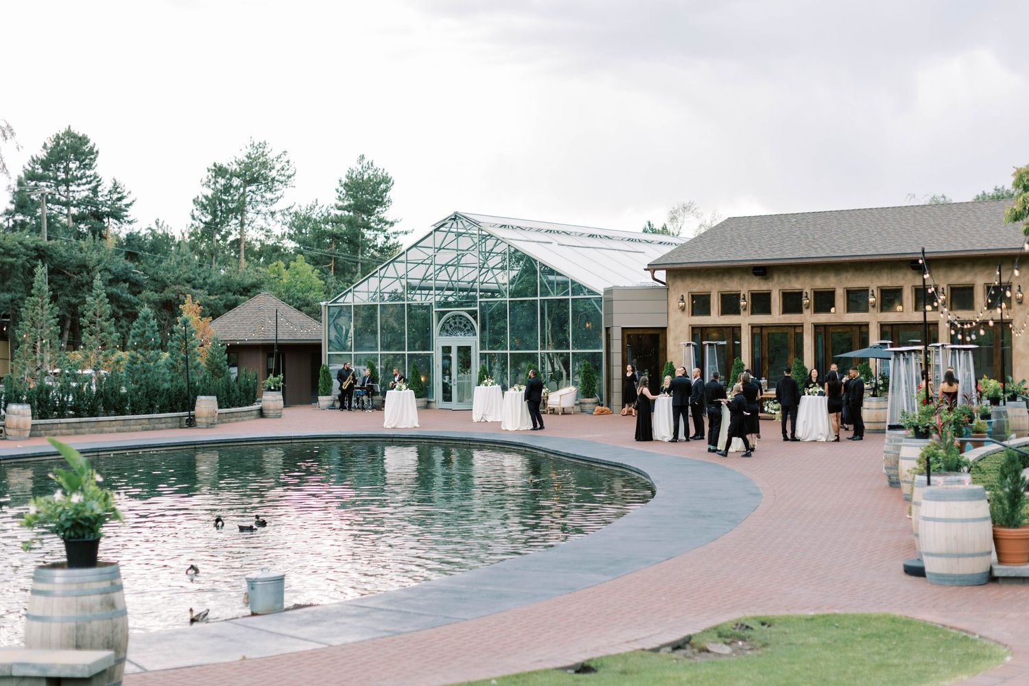 Beautiful greenhouse wedding venue with reflecting pool and brick pathway surrounded by gardens.