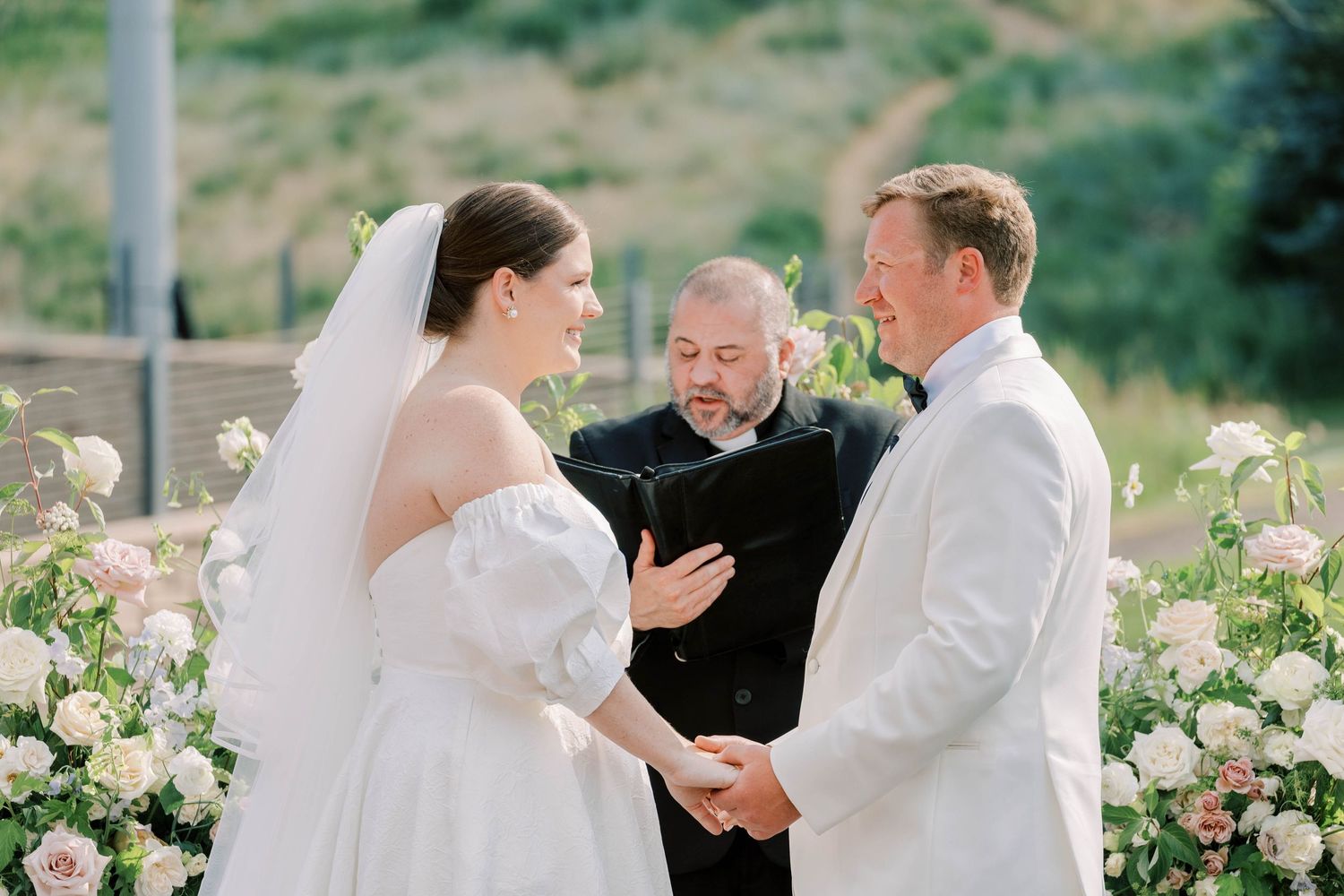 Wedding ceremony taking place on mountain venue deck with officiant and couple.