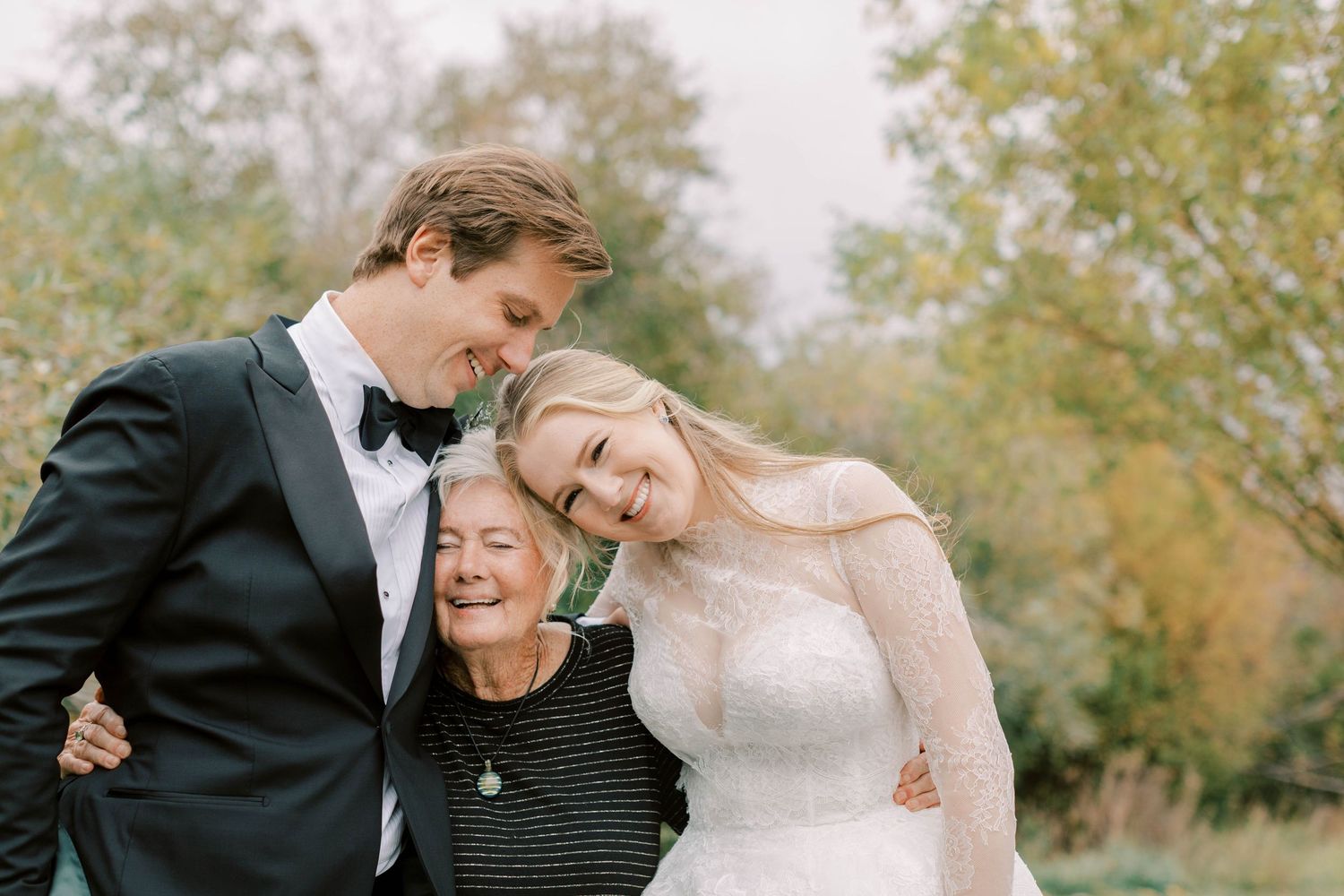 Joyful wedding moment shared between couple and elderly relative in outdoor setting.