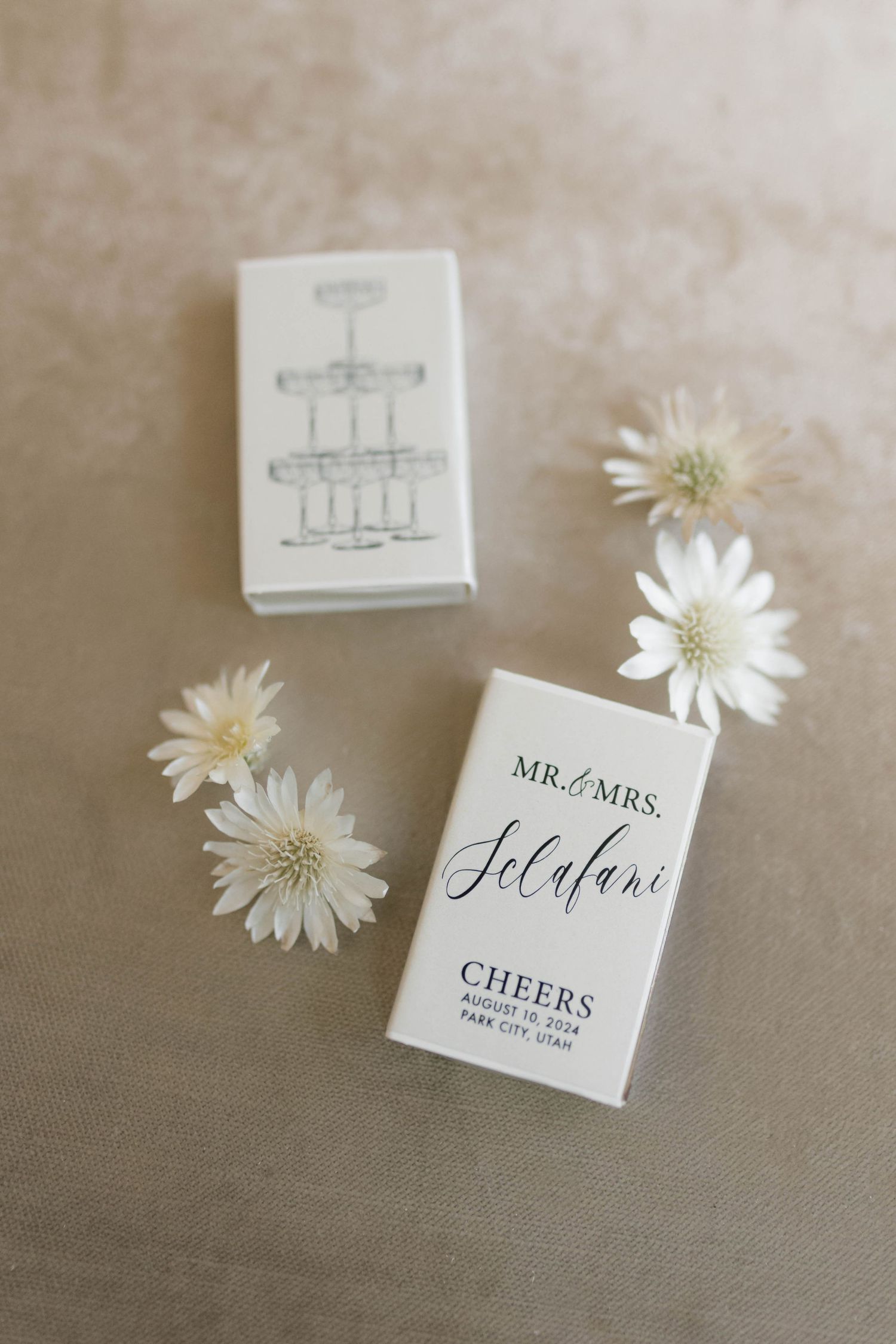 Wedding favor matchboxes with champagne tower design and couple's names.