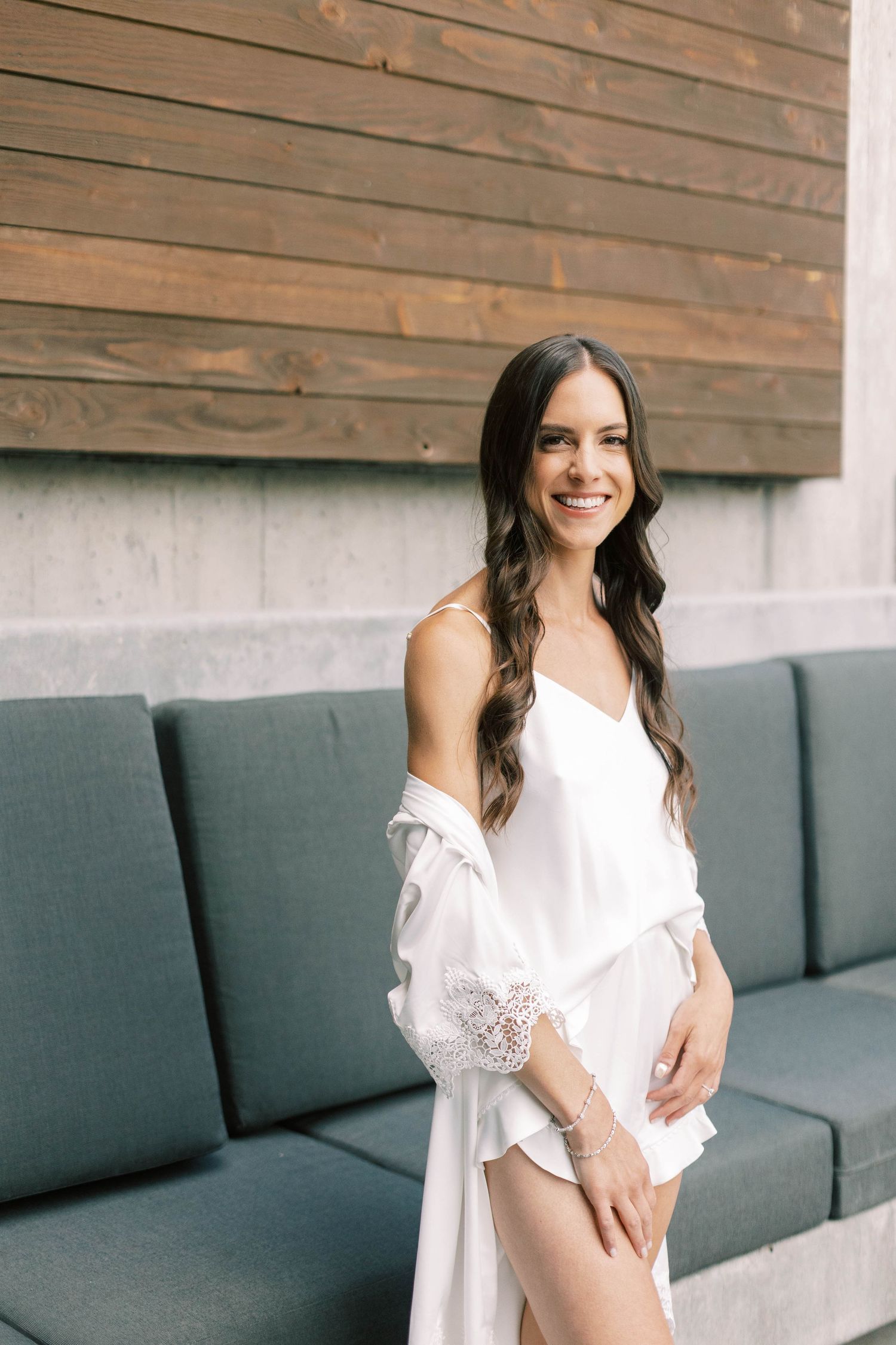A romantic bridal portrait featuring a white silk robe against a wooden wall backdrop.