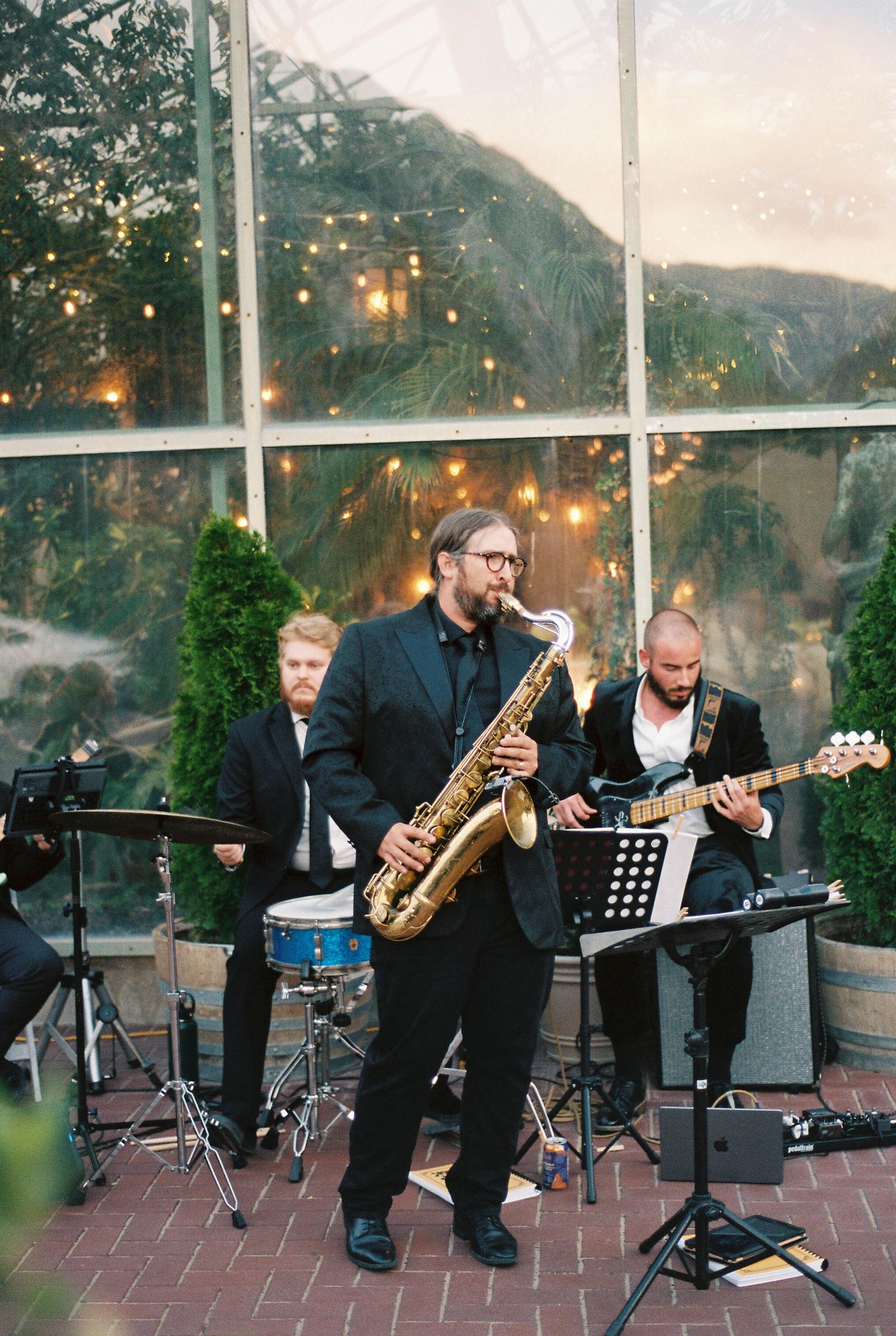 Live band performs with saxophone player and musicians at outdoor evening event.