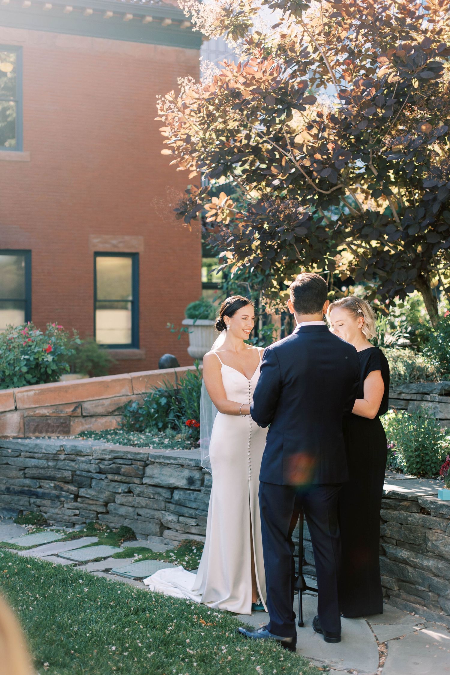 Outdoor ceremony moment on stone terrace with brick building backdrop.