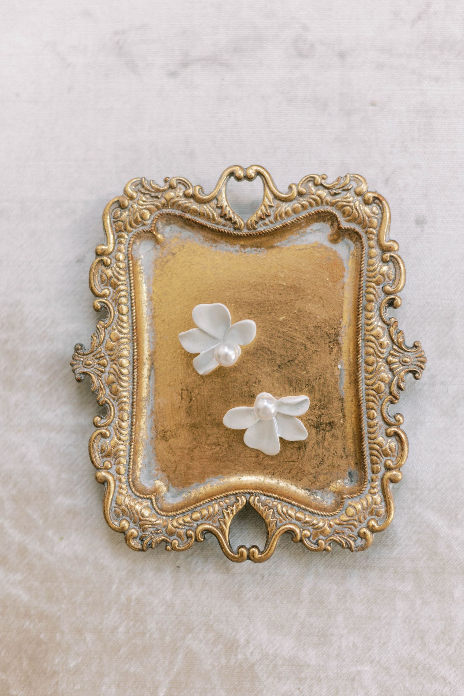 Ornate gold vintage tray displaying delicate white flower petals.