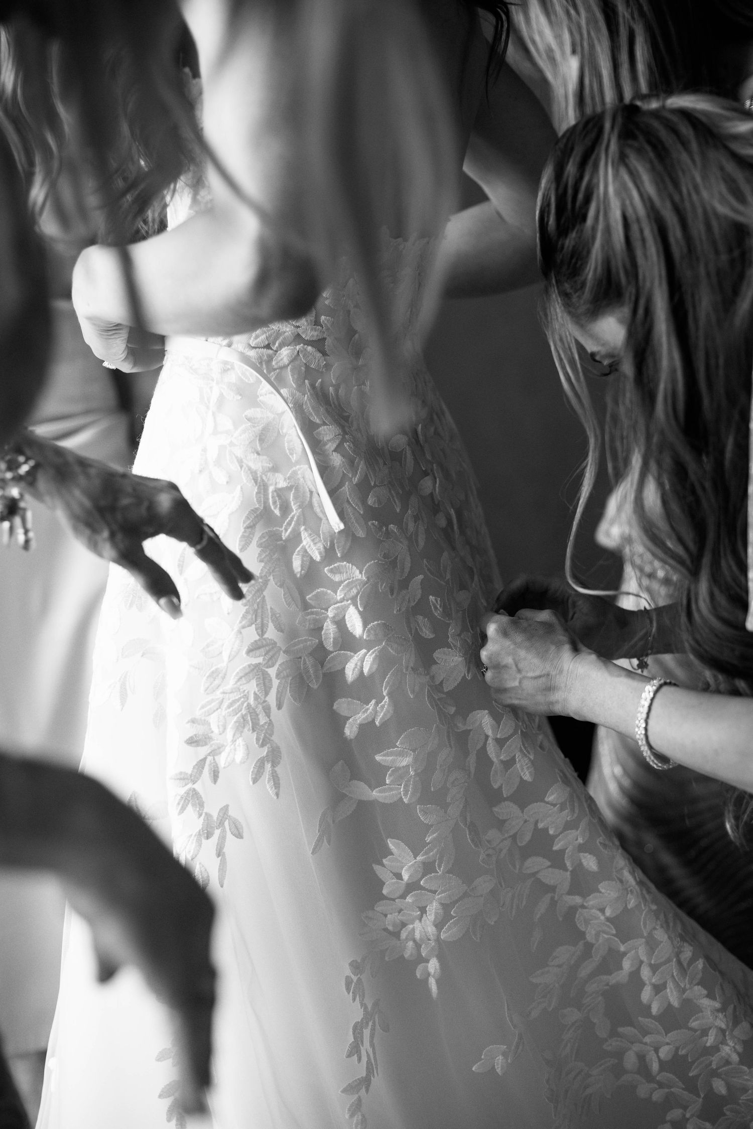 Black and white close-up of intricate lace dress details during wedding preparations.