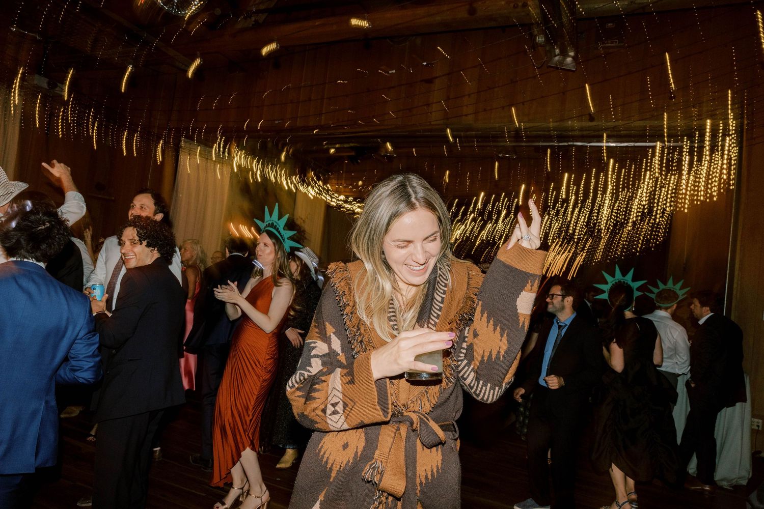 Guest enjoying a celebration under golden string lights at an indoor evening event.