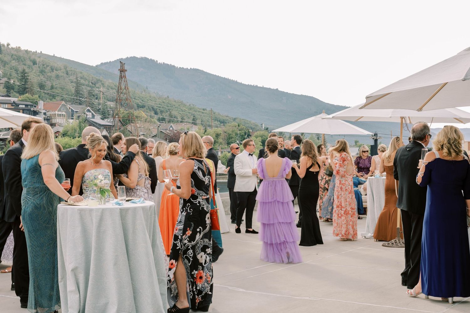Elegant outdoor reception with guests in formal attire mingling under white canopies.