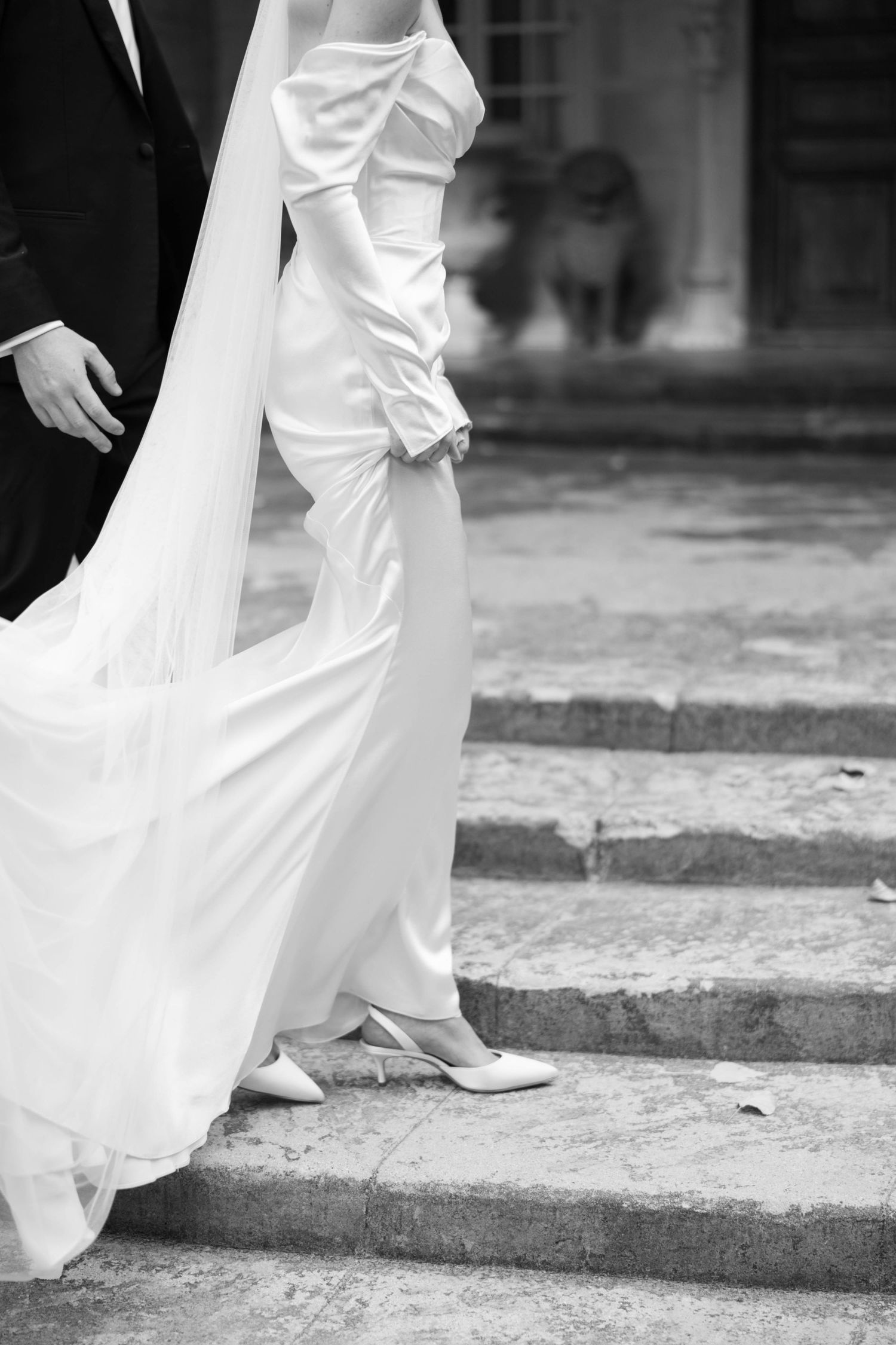 Close-up of a bride's white wedding dress and shoes as she ascends stone steps.