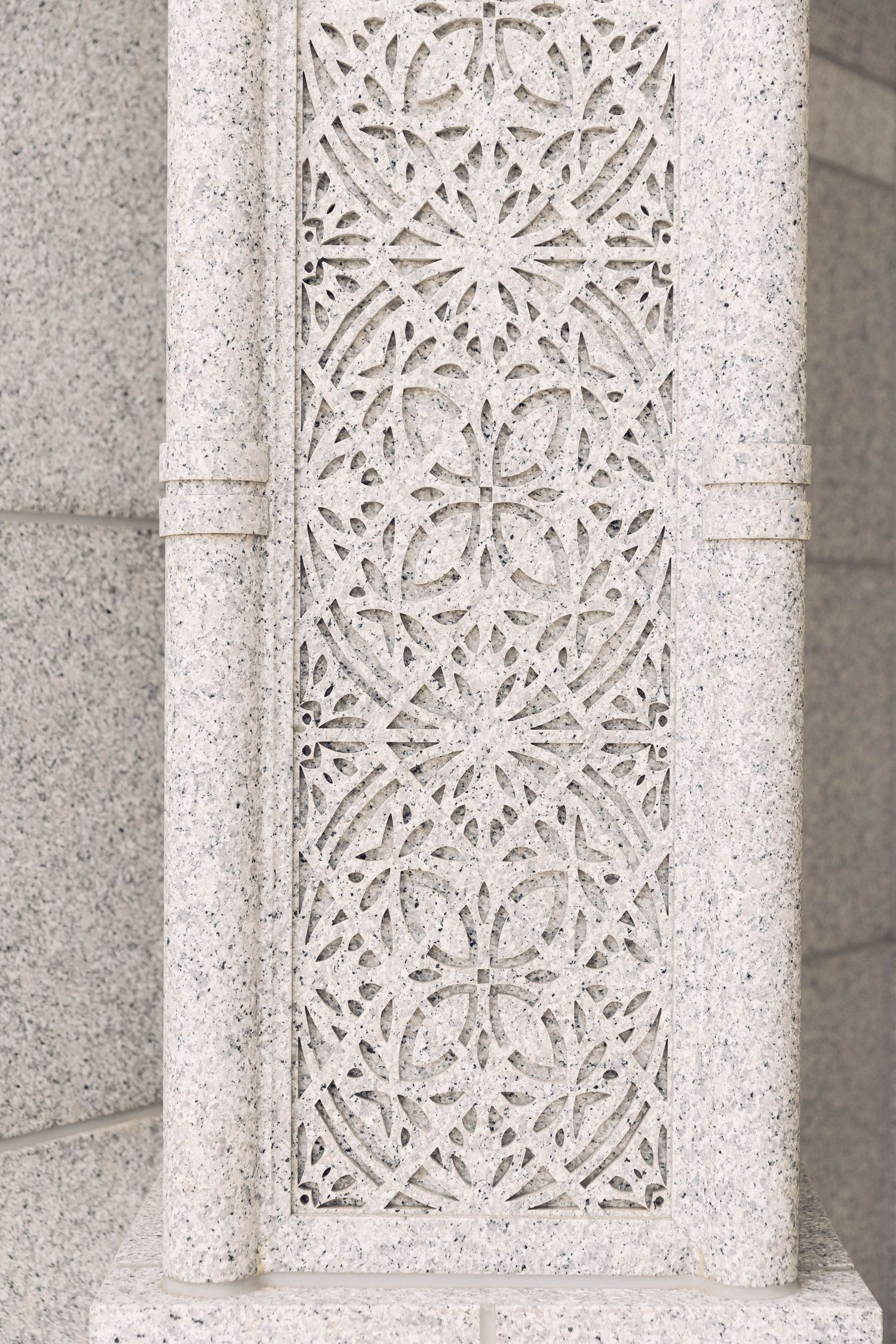 Intricate floral stone carving detail on temple wall with geometric patterns.