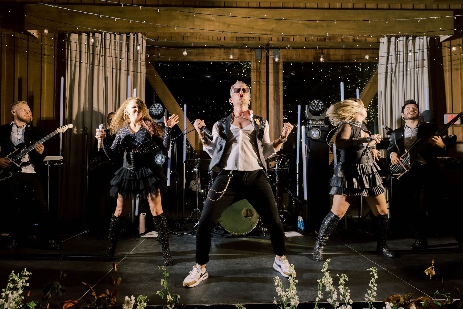 An energetic band performs on stage during a wedding reception.