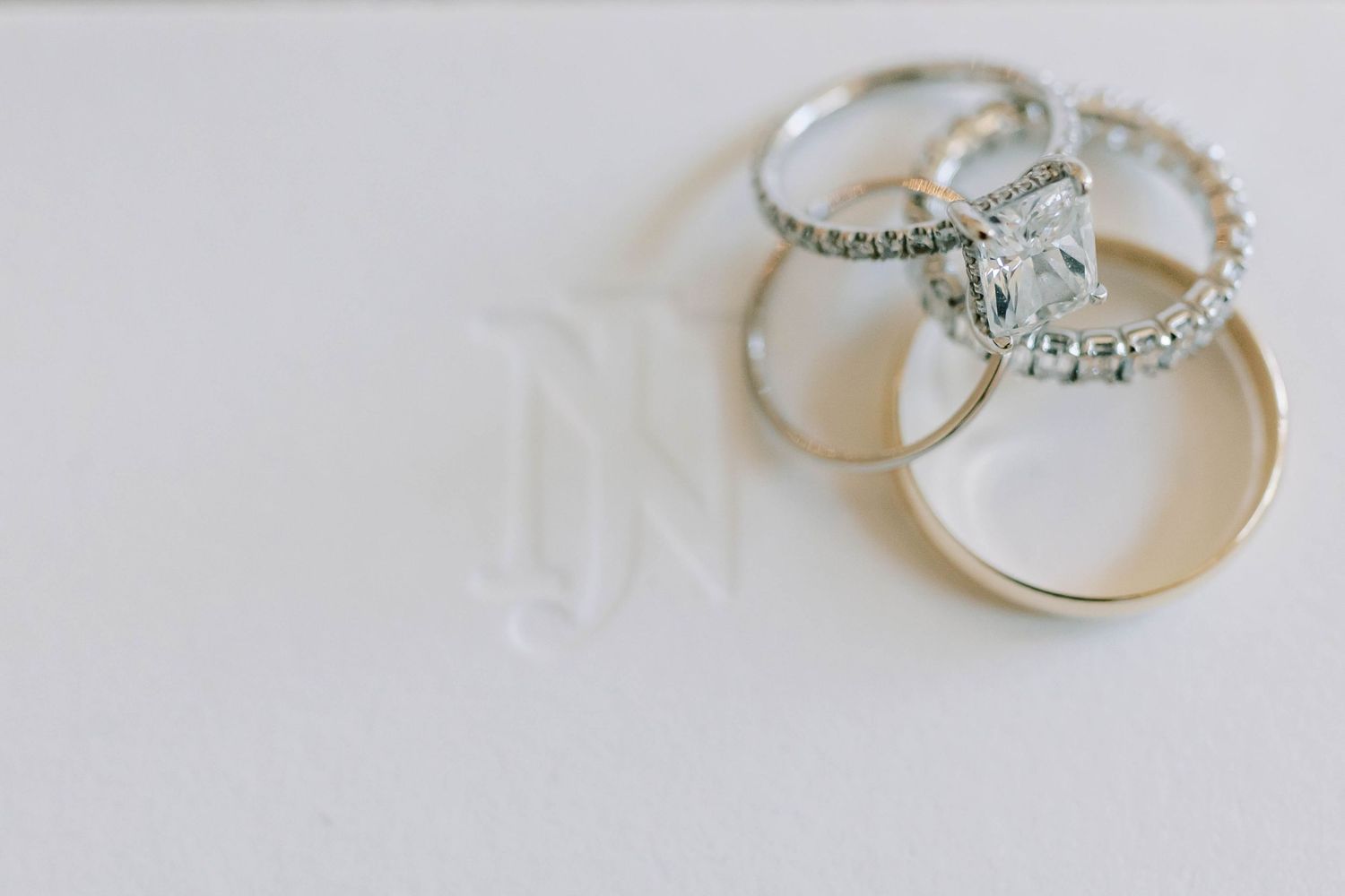 Three diamond and silver wedding rings arranged on a white surface.