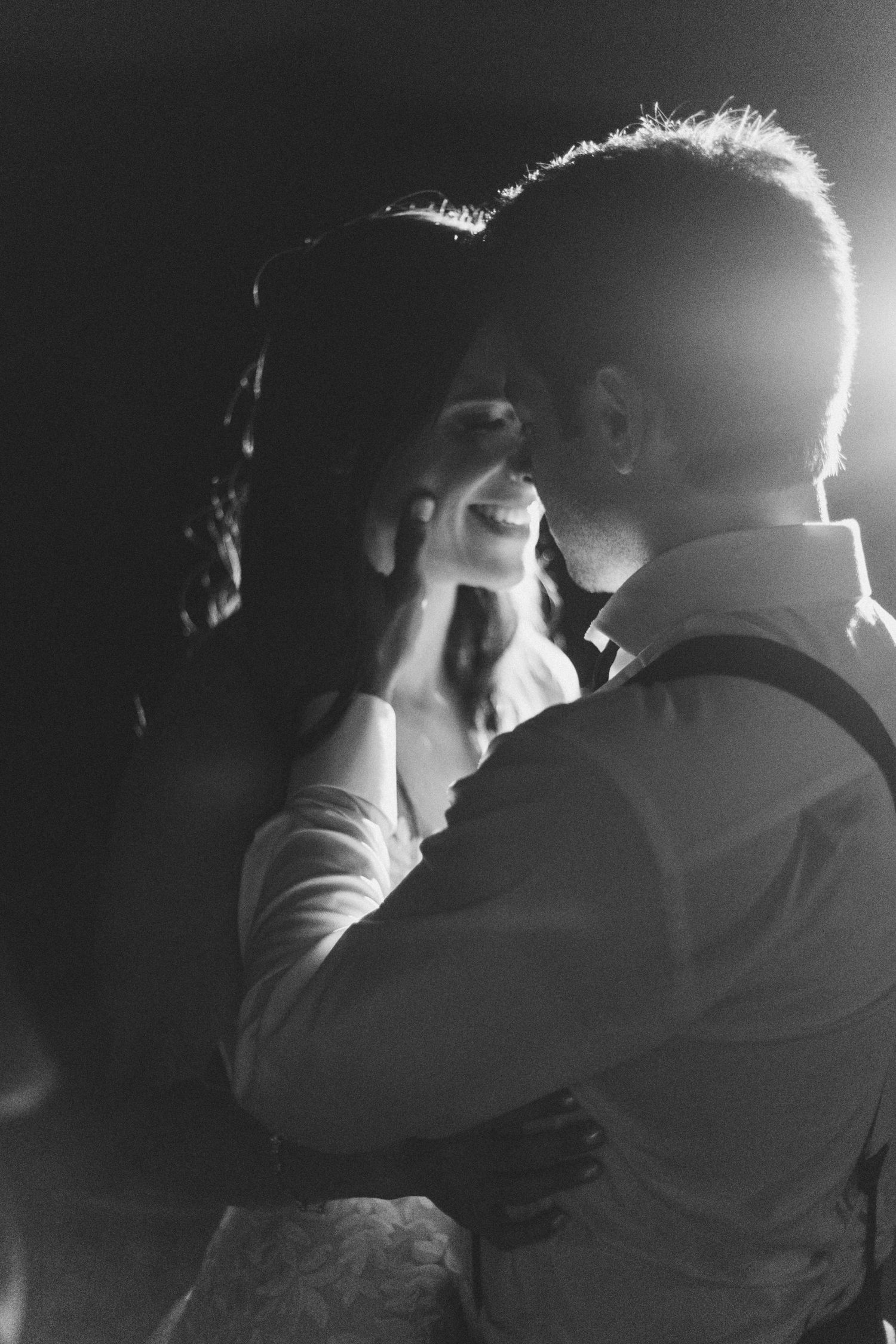 Silhouetted couple sharing intimate moment in dramatic backlit portrait.