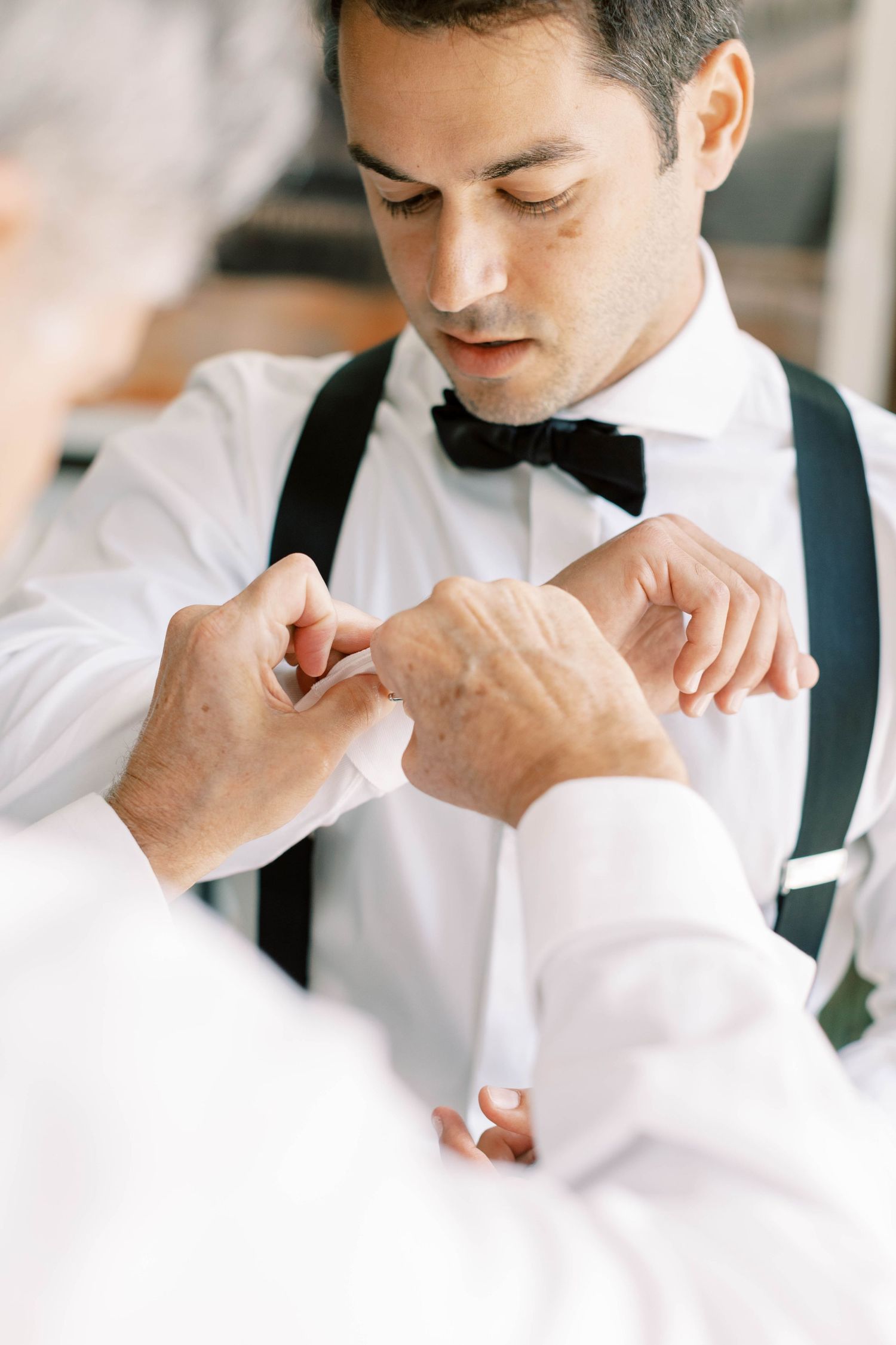 Wedding preparations showing hands adjusting formal attire.