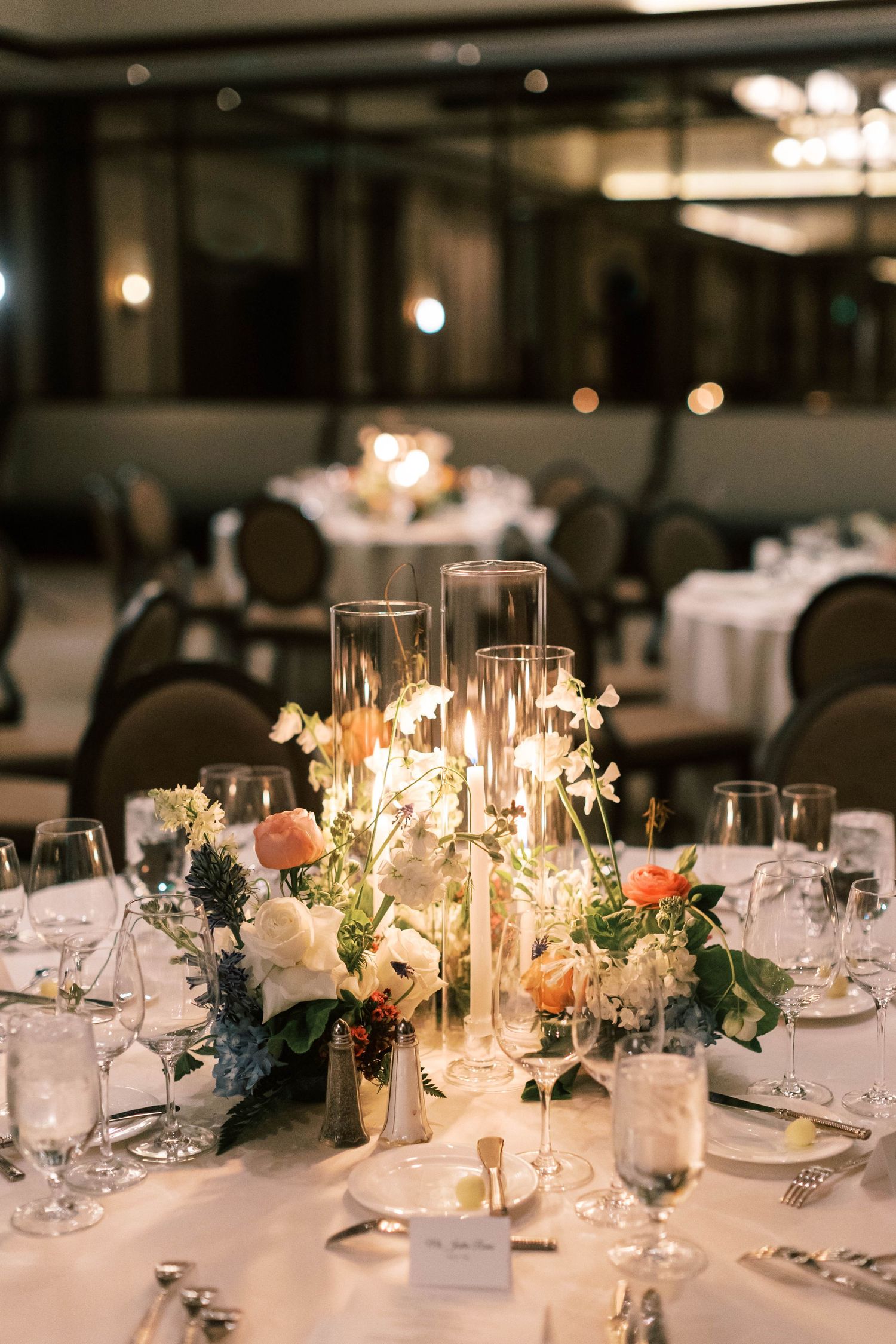 Romantic wedding table setting with glowing candles and white floral arrangements.