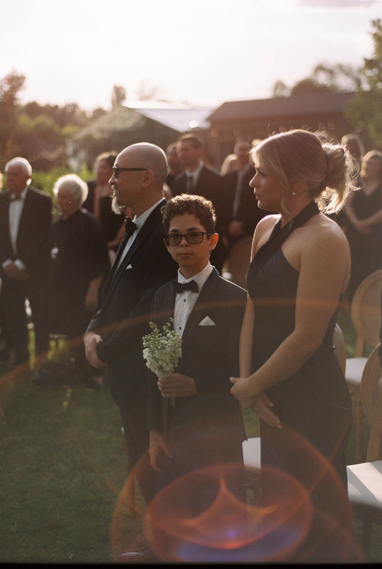 Sunset wedding ceremony gathering with formal attire and golden light.