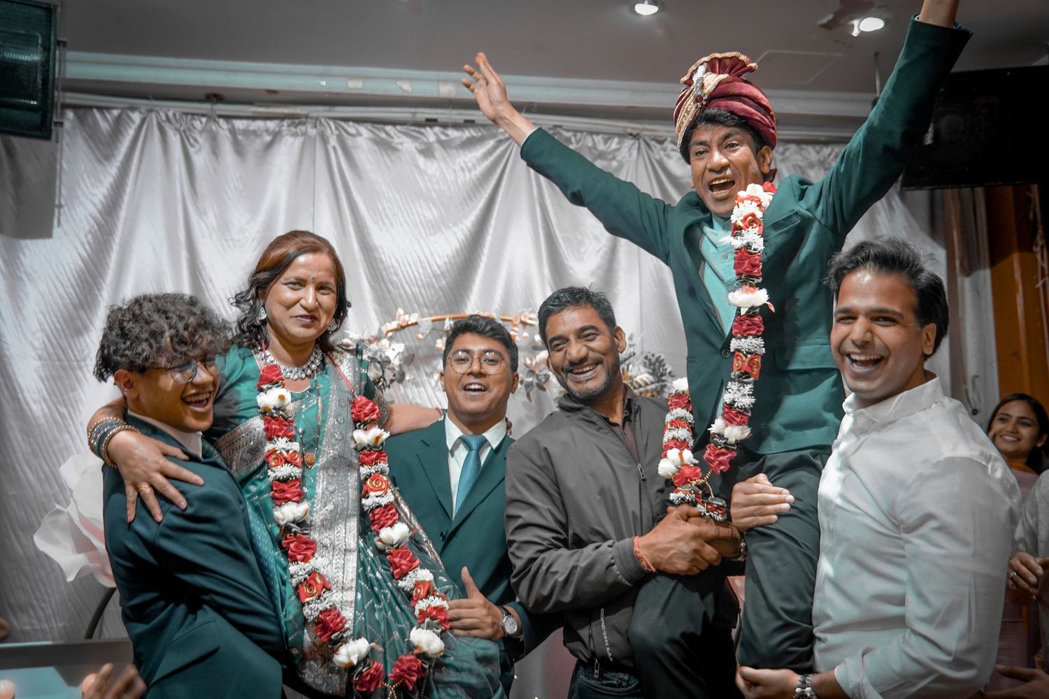 A joyous celebration at a traditional wedding reception shows the festive bridal party in matching floral garlands.